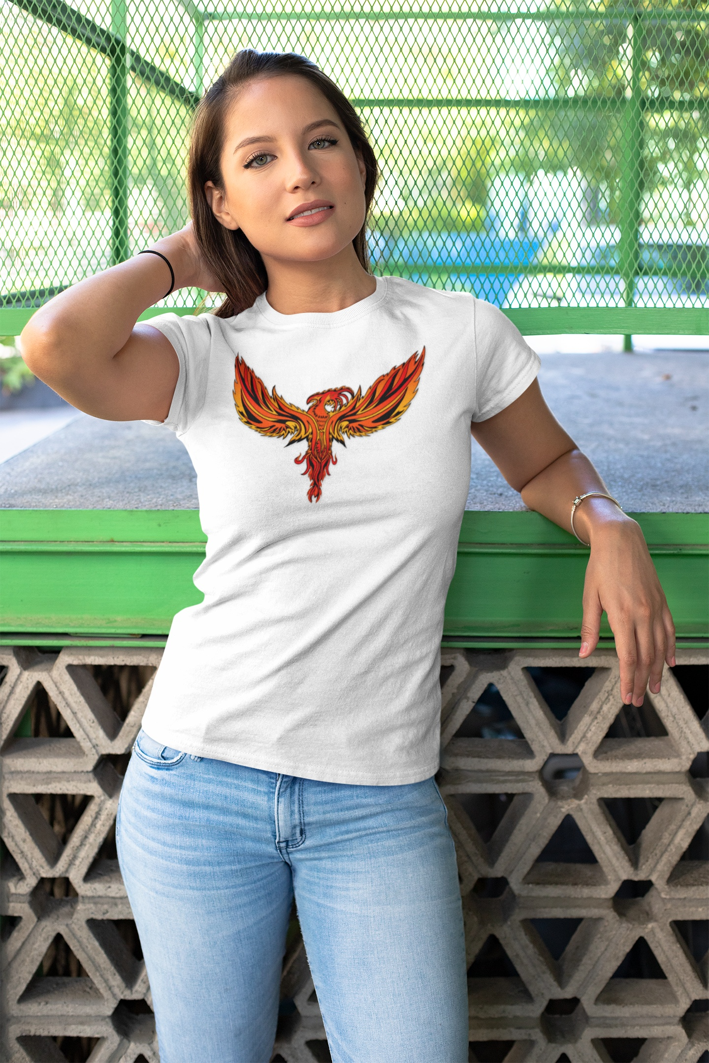Woman wearing white Phoenix Tee with vibrant fiery phoenix design, casual outdoor setting.