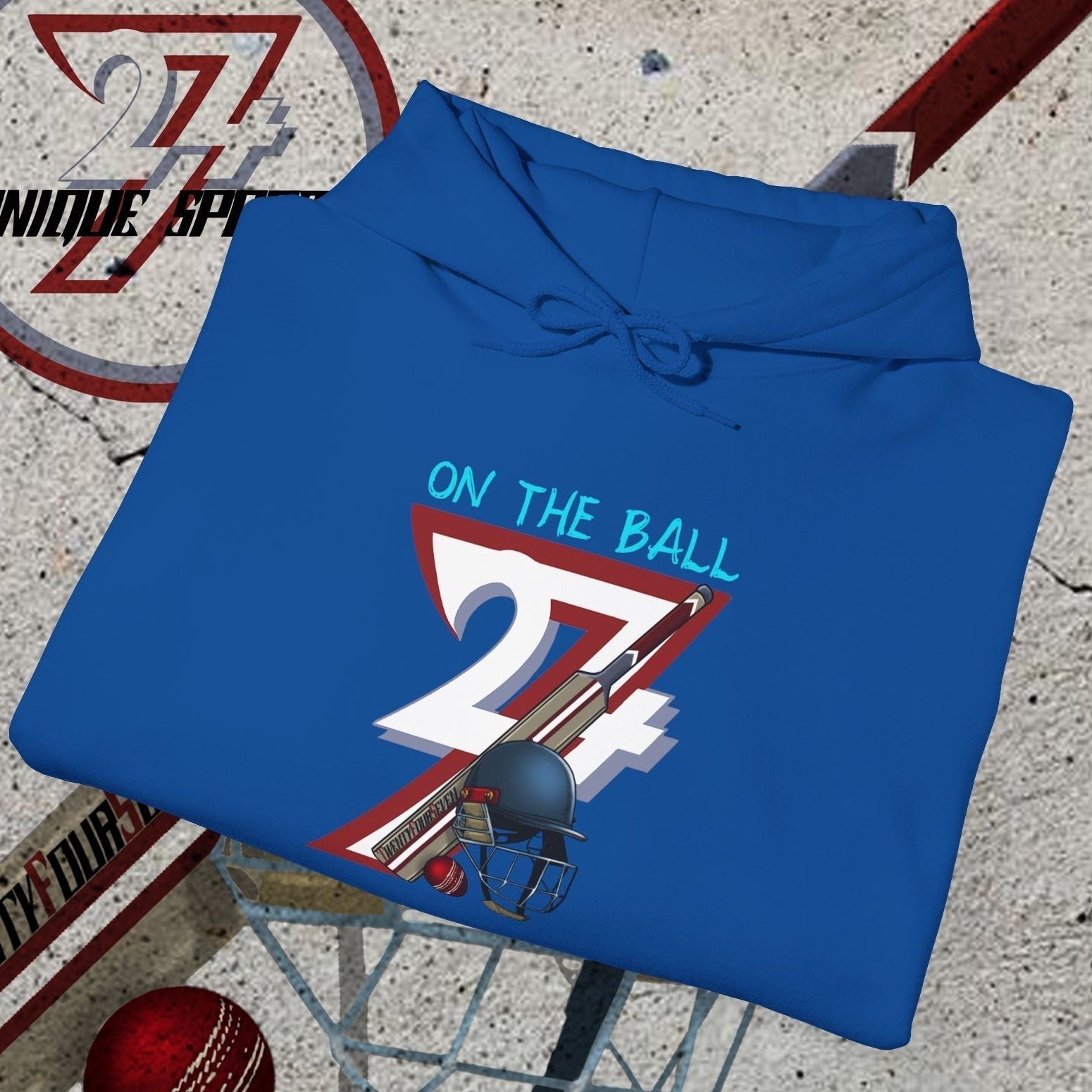 Blue cricket hoodie sweatshirt with unique "On The Ball 24/7" illustration and cricket gear graphics