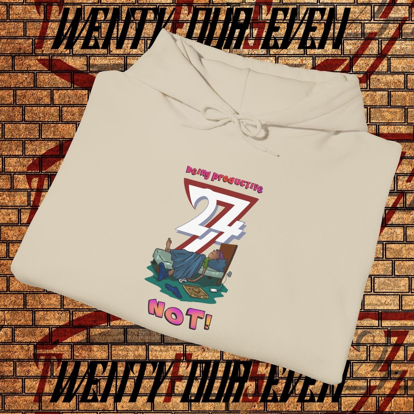 Folded beige funny custom hoodie with colorful lazy teen cartoon design on front against brick wall background