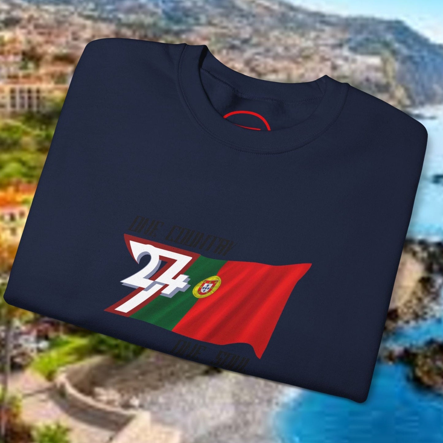 Folded navy Portugal Flag Sweatshirt with vibrant hand-drawn football design on scenic coastal background