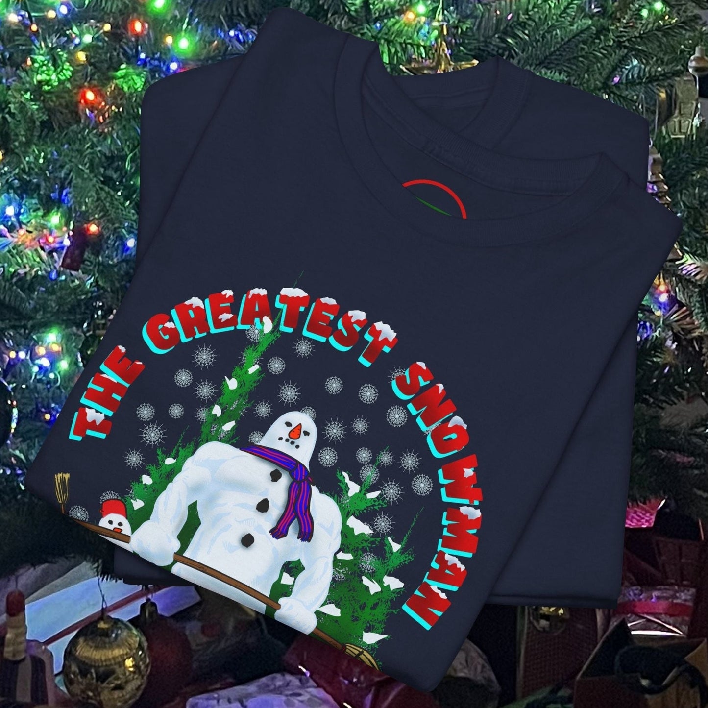 Folded navy blue snowman gym t-shirt with cartoon snowman lifting dumbbells and holiday text, placed under Christmas tree lights