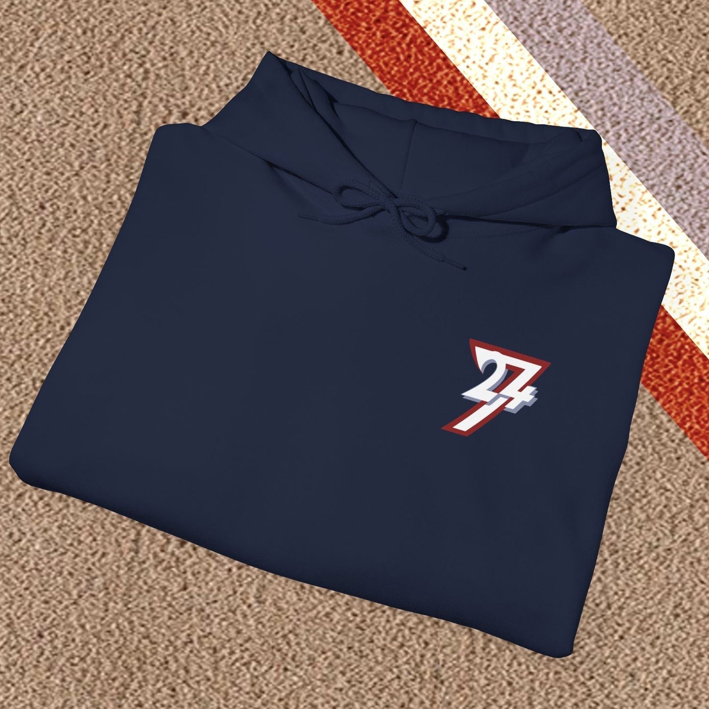 Folded navy blue stylish hoodie with twentyfourseven logo on carpet background
