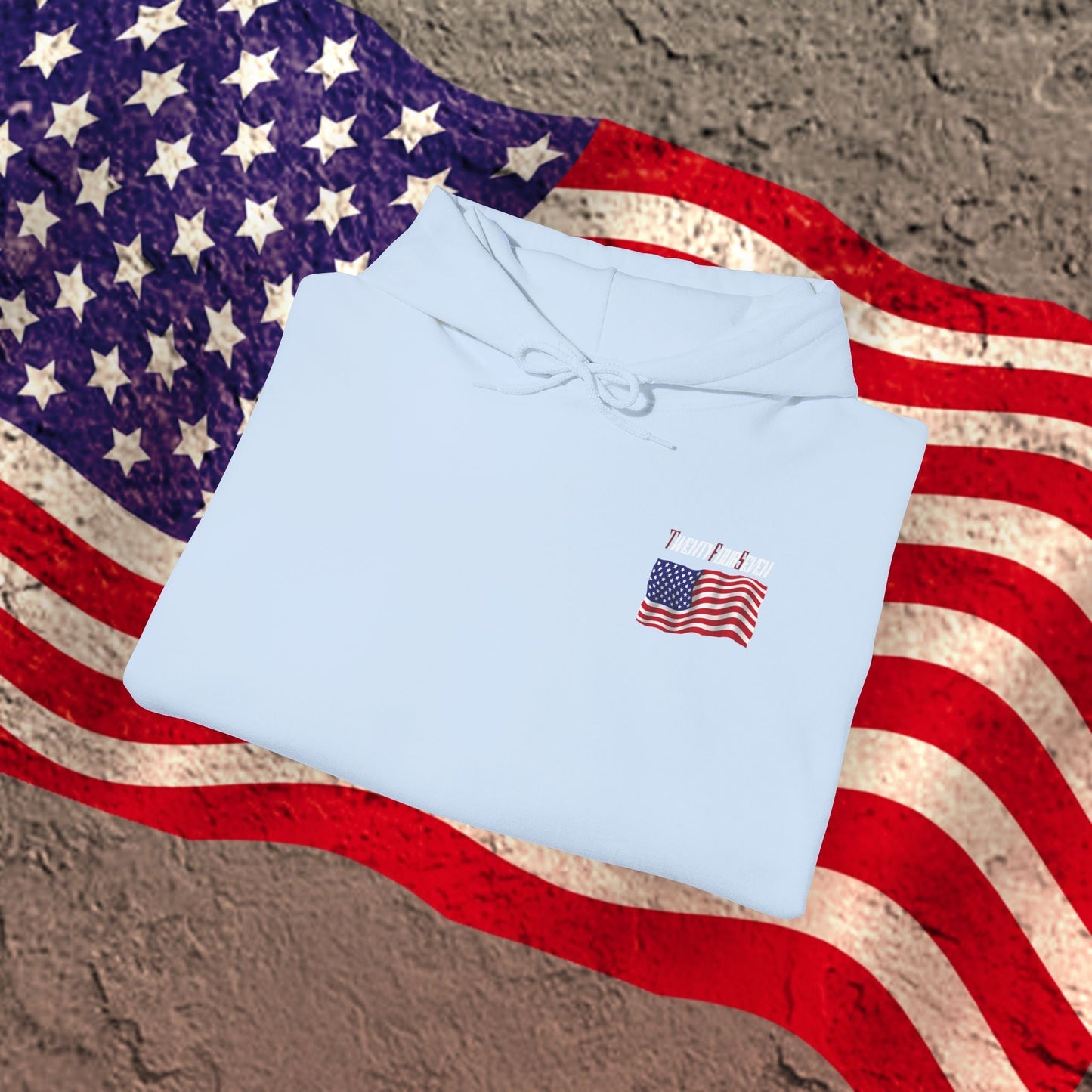 Light blue US flag hoodie with small American flag design on chest, displayed on vintage American flag background