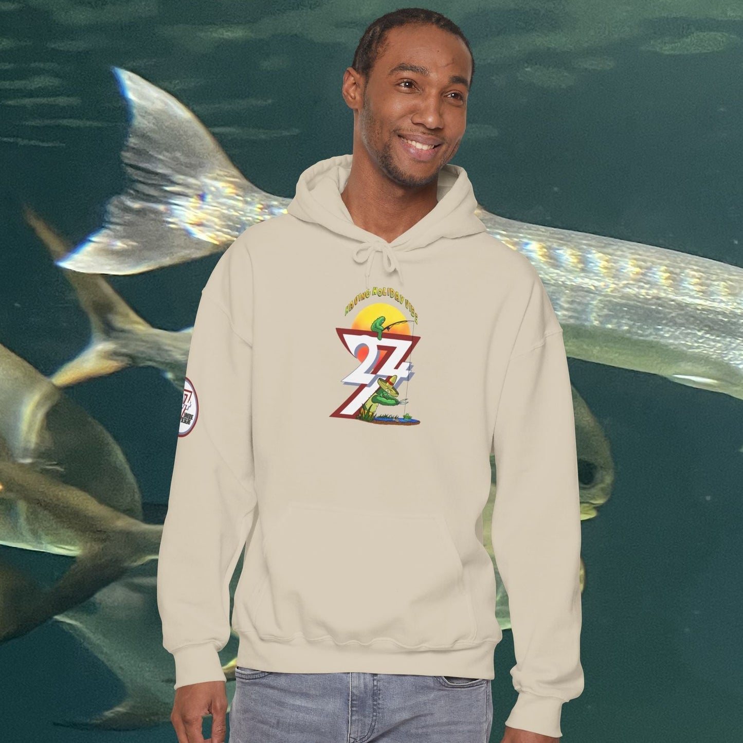 Man wearing Funny Fishing Hoodie with cactus design standing in front of underwater fish background