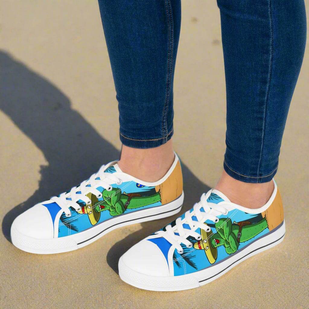 White low top sneakers with colorful tropical cactus and beach design, worn with blue jeans on sand, Tropic Feel sneakers for women