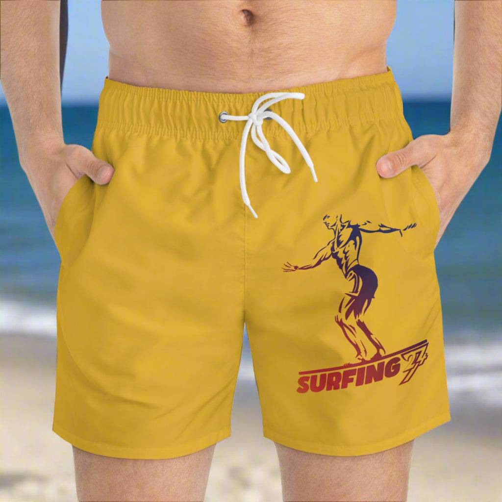 Yellow surfer swim trunks with adjustable white drawstring and surfer illustration on the front, beach background