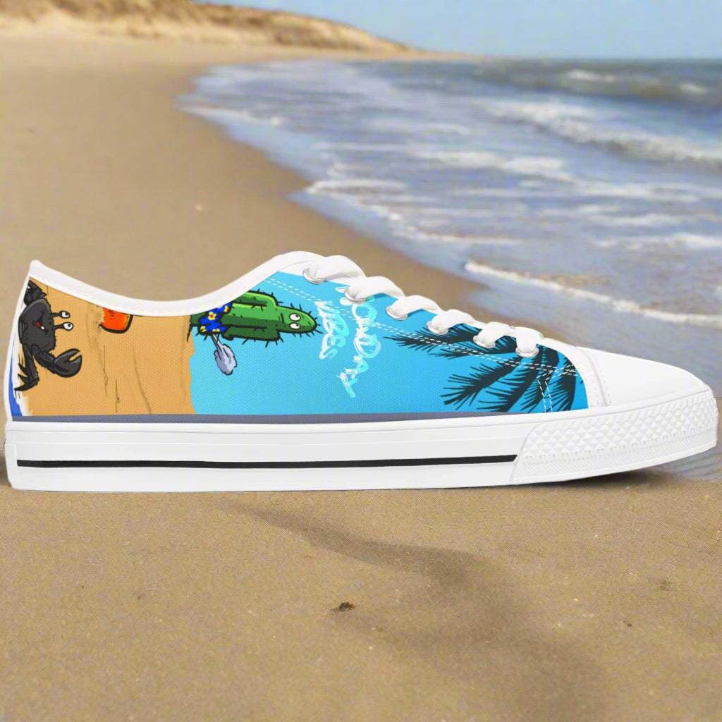 White low top Tropic Feel sneakers for women with fun beach-themed design featuring palm trees, cactus, and a crab, displayed on sandy beach background.