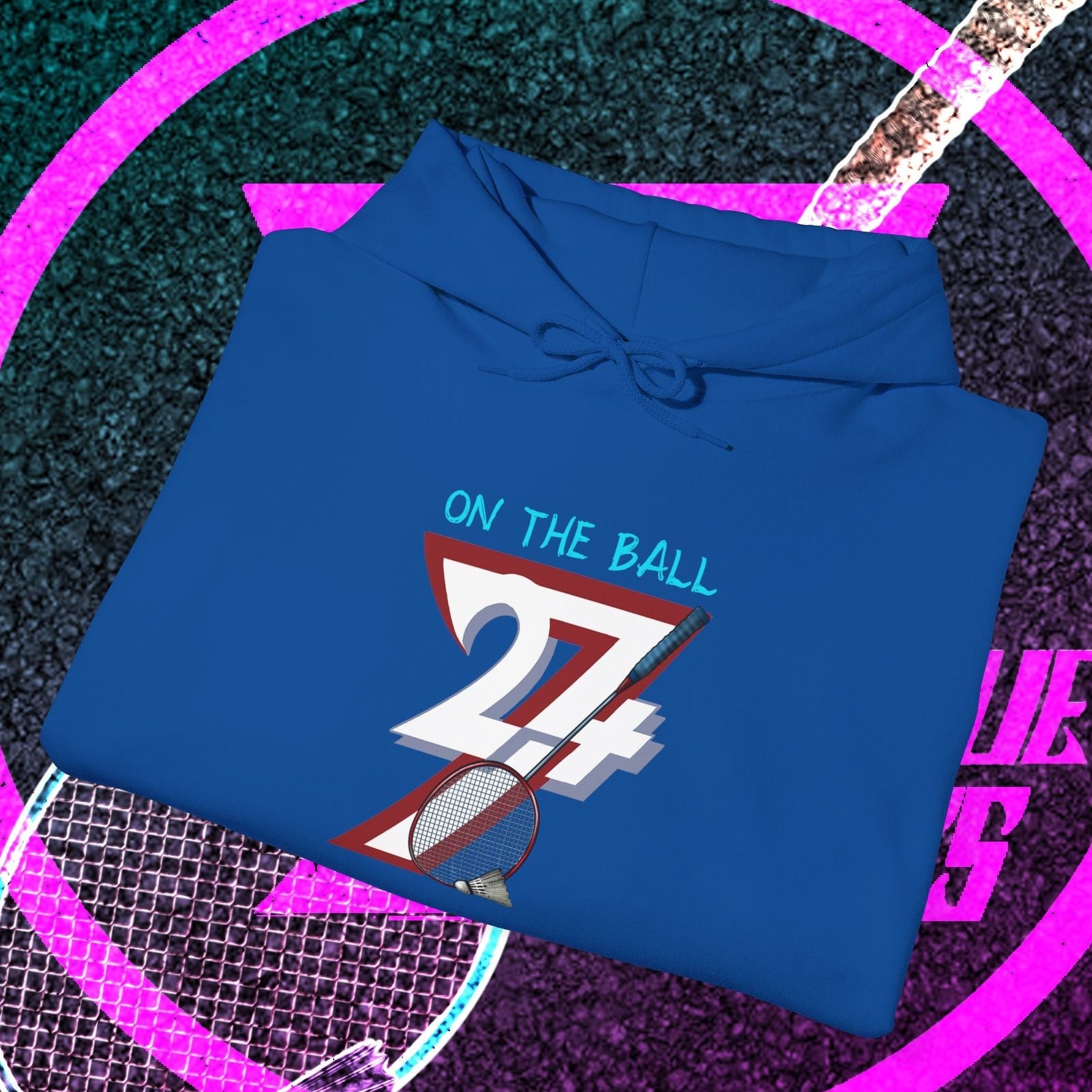 blue badminton hoodie sweatshirt with "On The Ball 24/7" graphic design folded on colorful sports-themed background