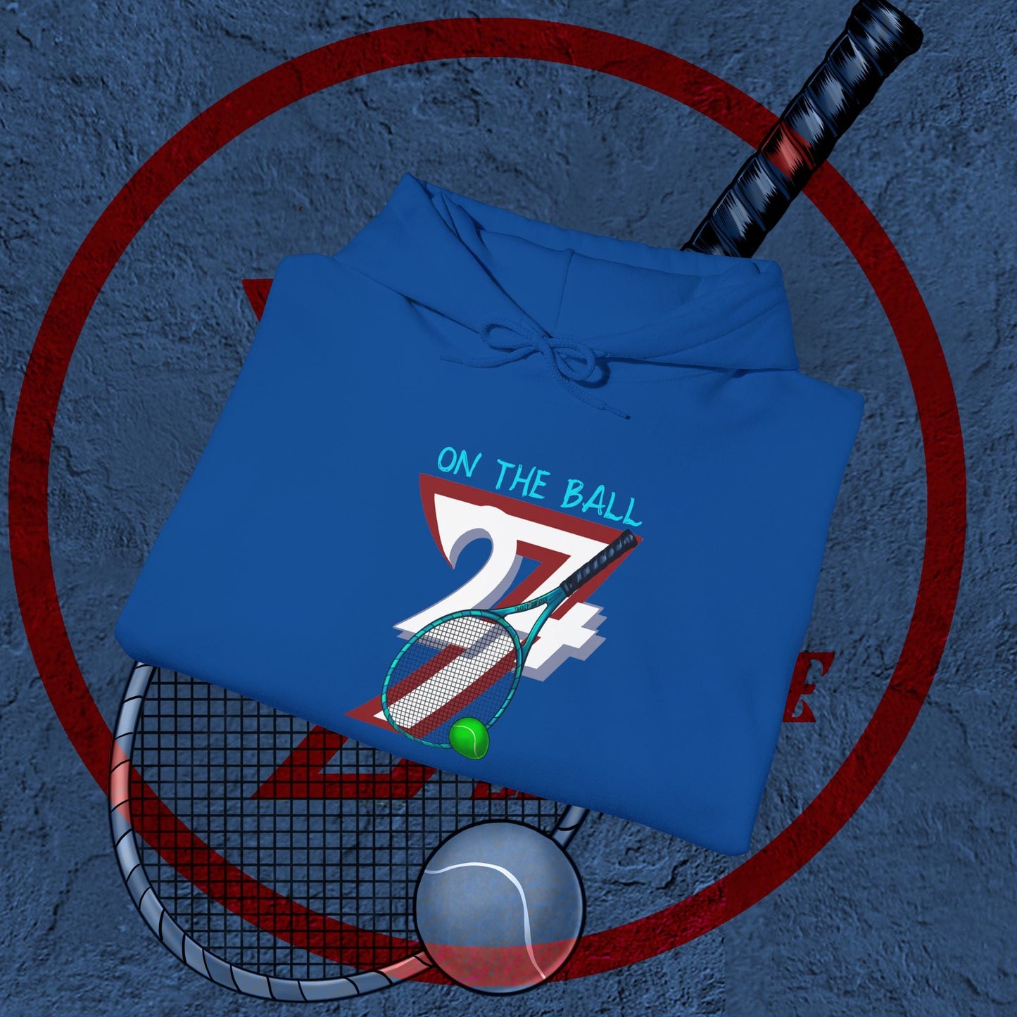 blue tennis hoodie with hand-drawn tennis gear design and "On the Ball" text, folded on textured surface with tennis racket and ball background