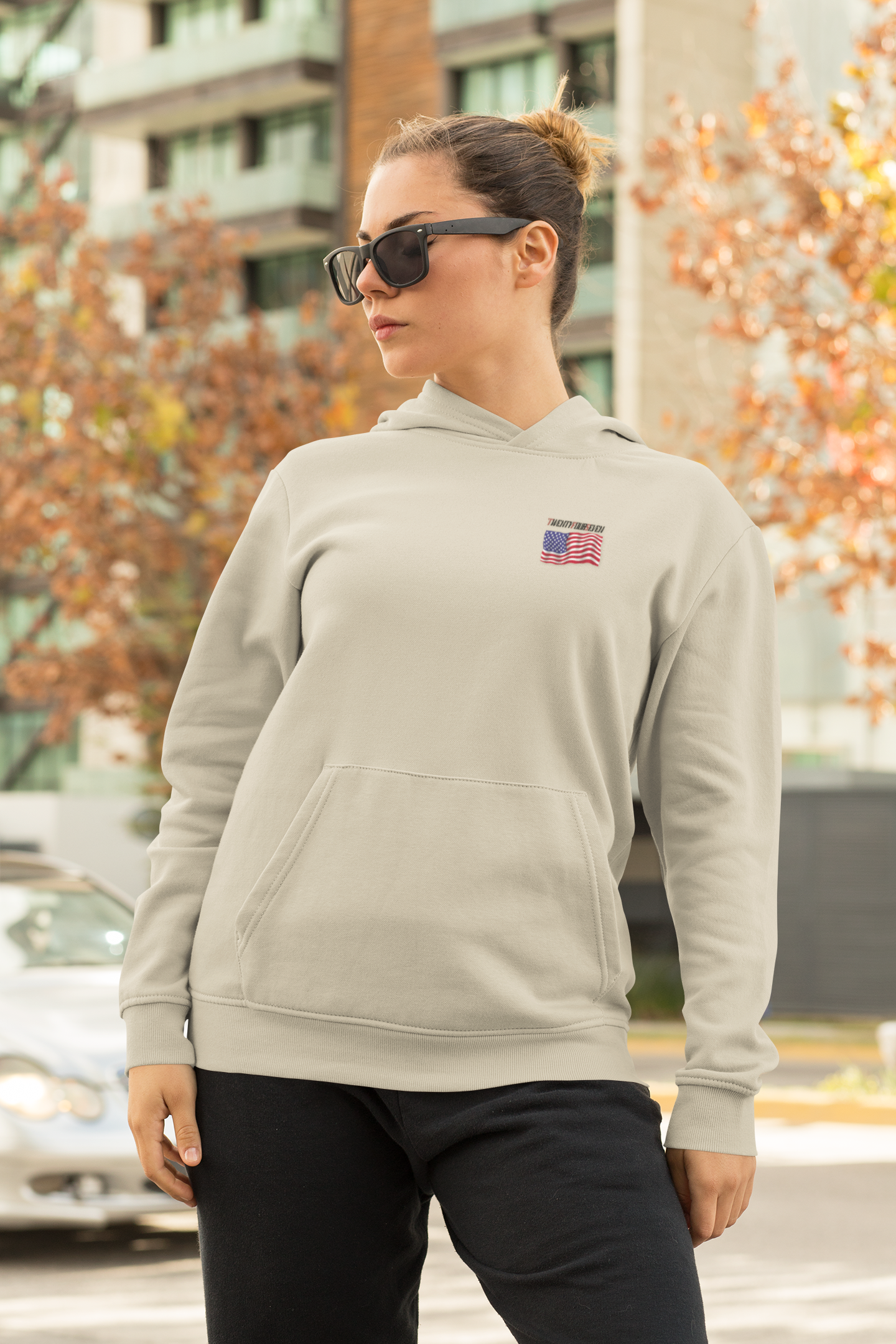 woman wearing beige American flag hoodie with small US flag logo and sunglasses outdoors