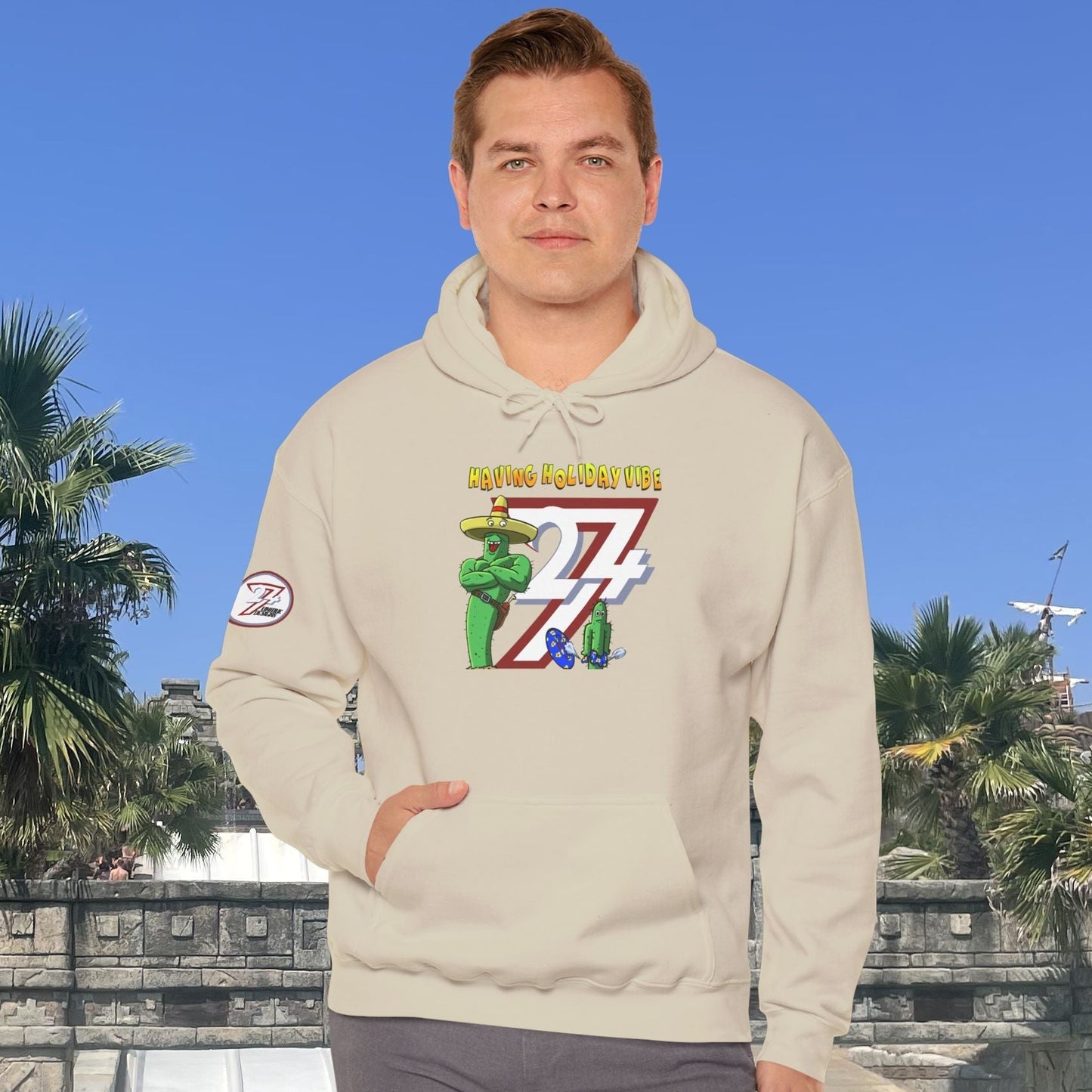 Adult wearing beige cactus hoodie with cartoon design, kangaroo pocket, and drawstring hood in outdoor sunny setting