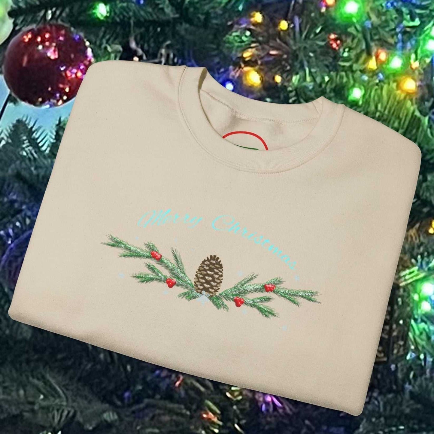 Beige Pinecone Christmas Sweatshirt with hand-drawn pinecone and pine branch design, folded on festive Christmas tree background with colorful lights.