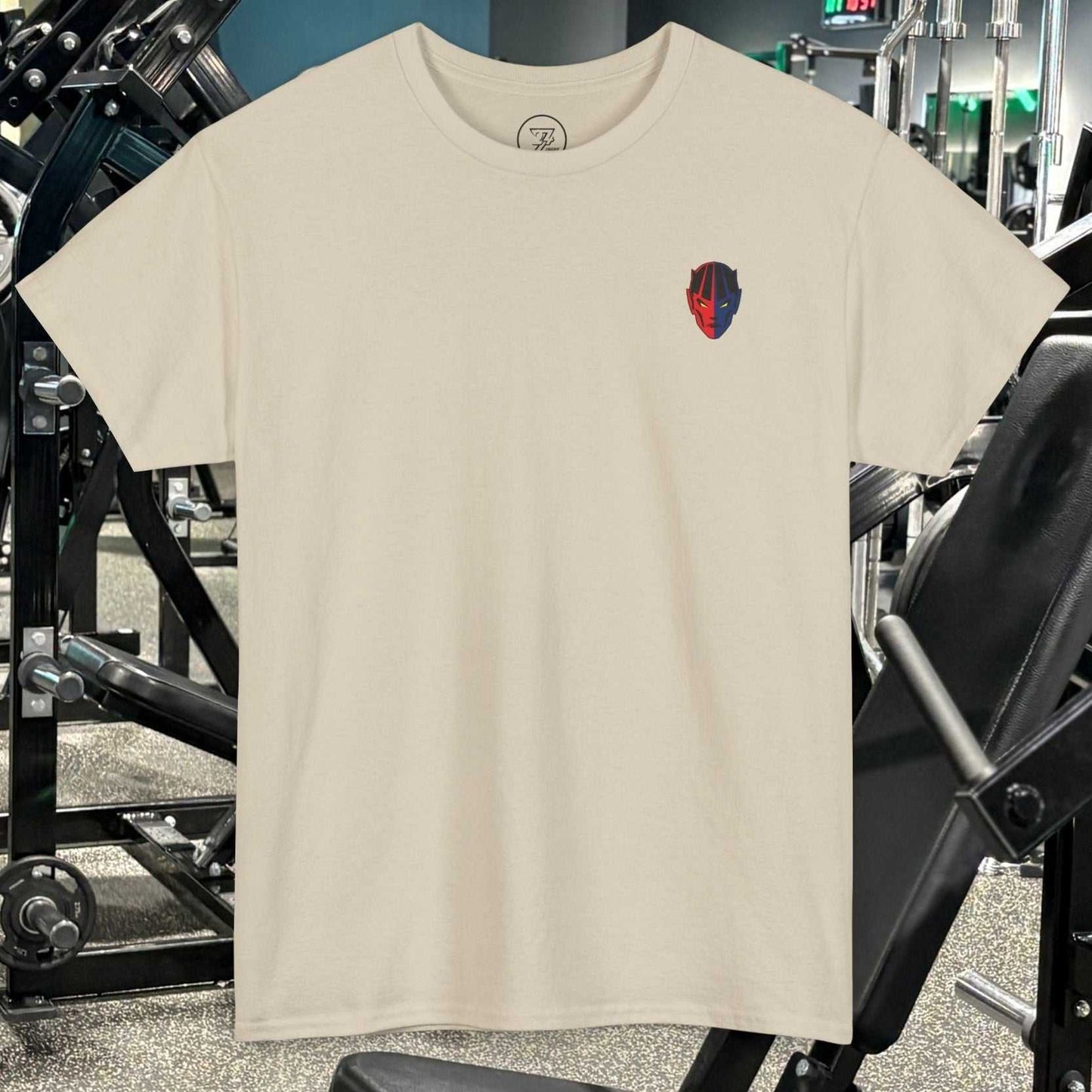 Beige bodybuilding tee with small red and blue gym logo on chest, displayed in a gym setting