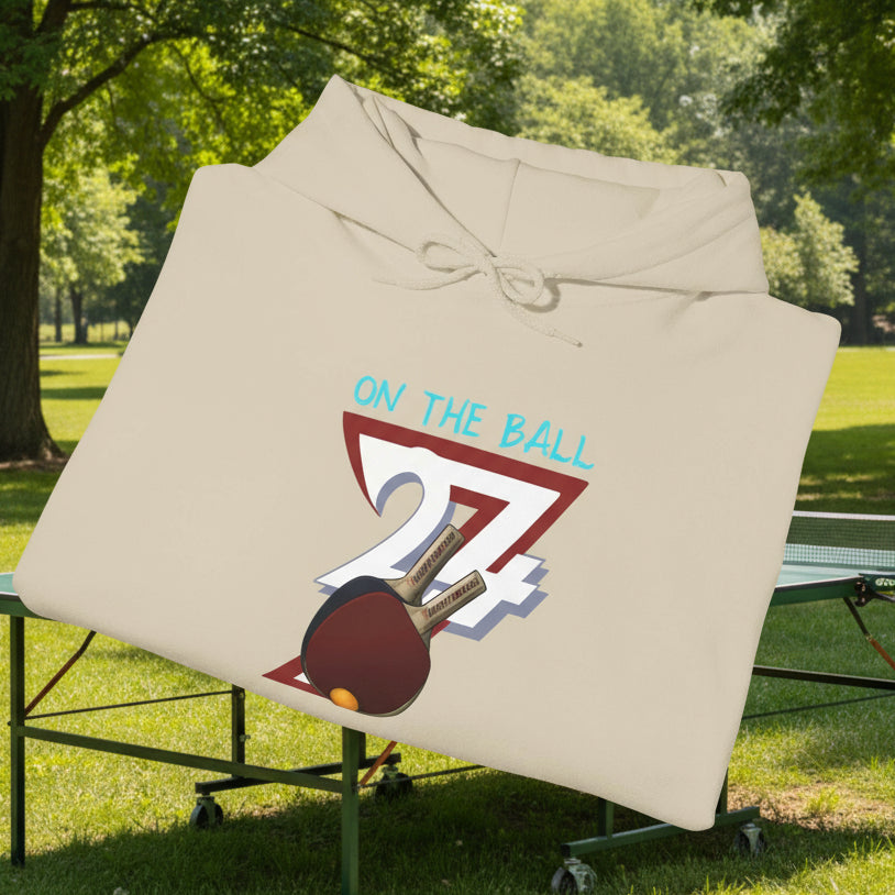 Beige ping pong hoodie with hand-drawn table tennis paddle and ball design, adjustable hood and kangaroo pocket.