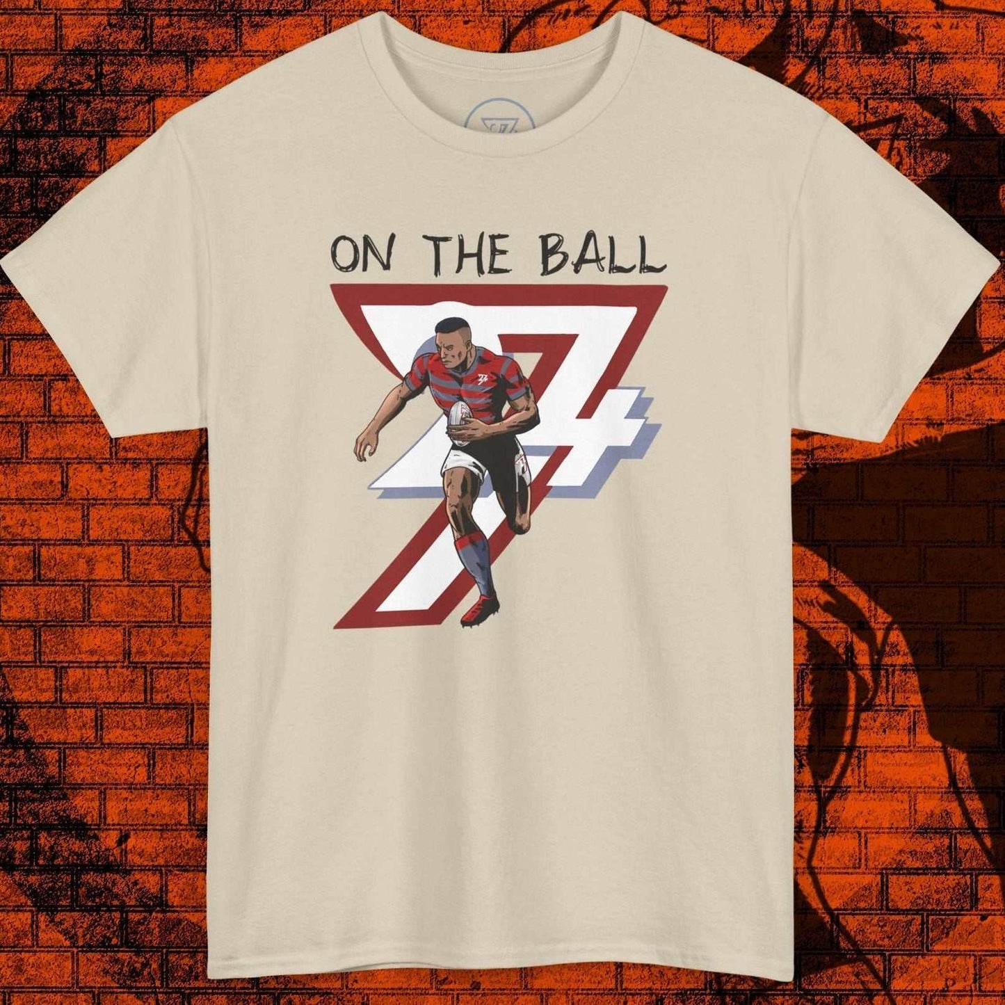 Beige rugby sports tee with hand-drawn illustration of a player running with the ball and text "On The Ball"