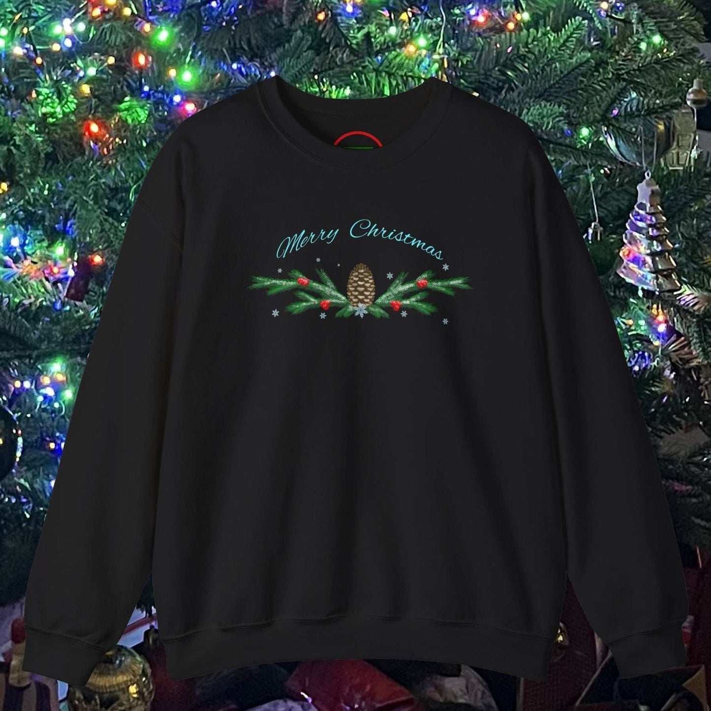 Black Pinecone Christmas Sweatshirt with festive pinecone and holly design hanging against a decorated Christmas tree background