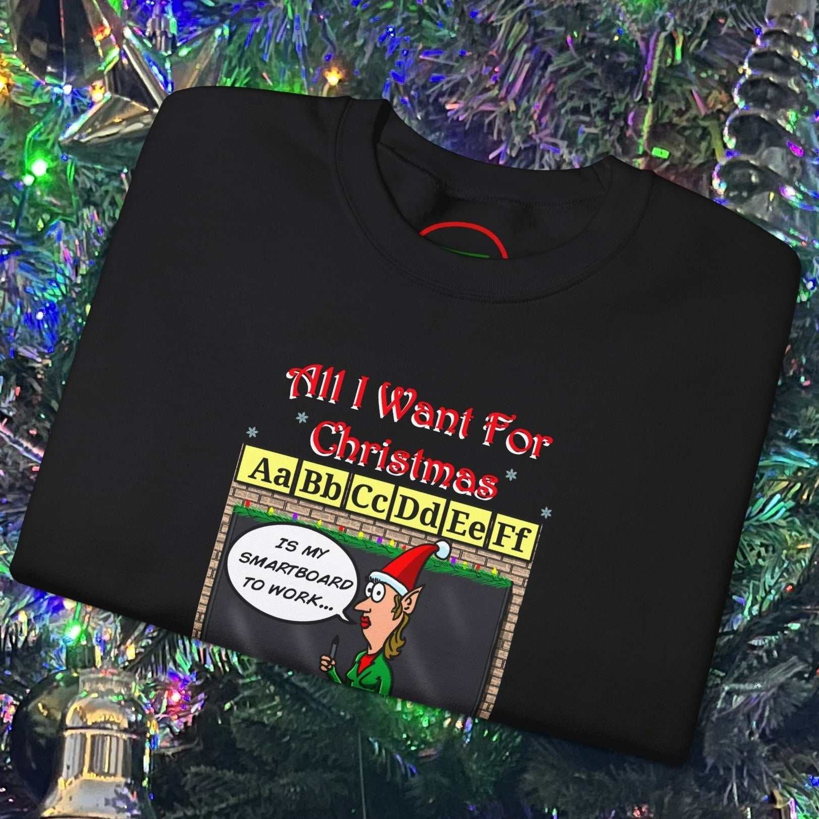 Black Teacher Christmas Sweatshirt with funny cartoon teacher and holiday-themed text design on folded fabric against Christmas tree background