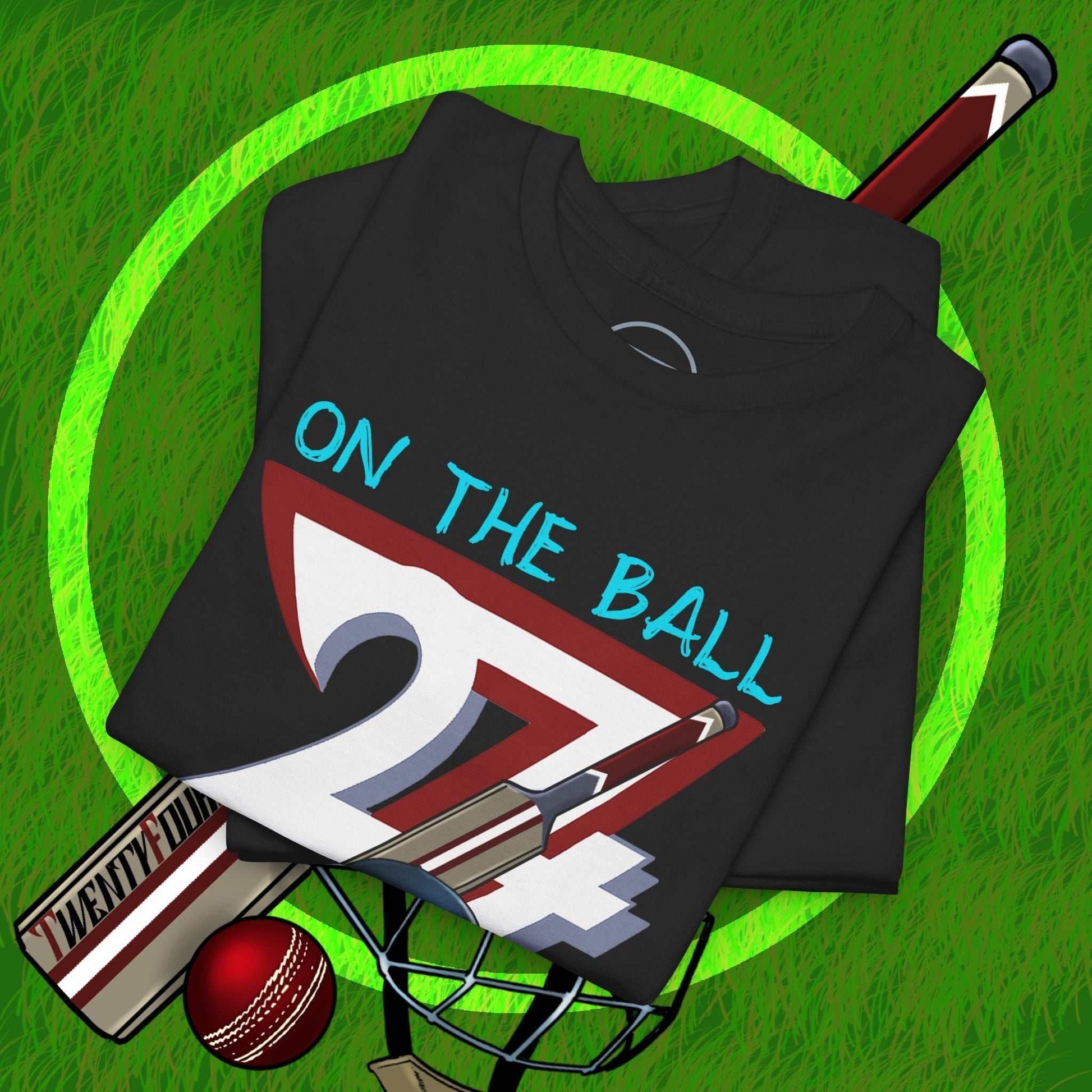 Black cricket tee with hand-drawn "On The Ball 24/7" design, featuring cricket bat and ball on green grass background