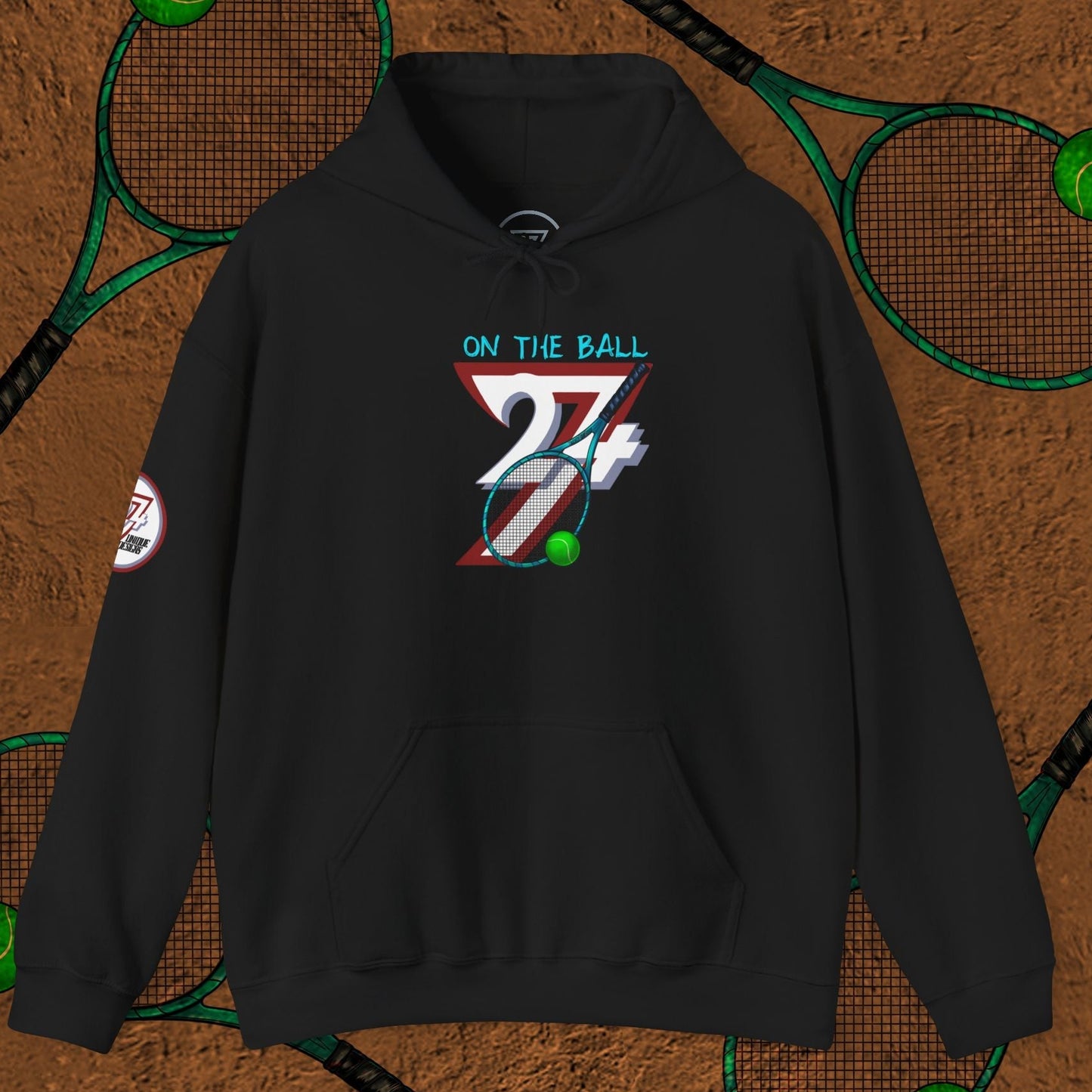 Black tennis hoodie with hand-drawn tennis gear design and "On The Ball" text on front, displayed on tennis court background with rackets and balls.