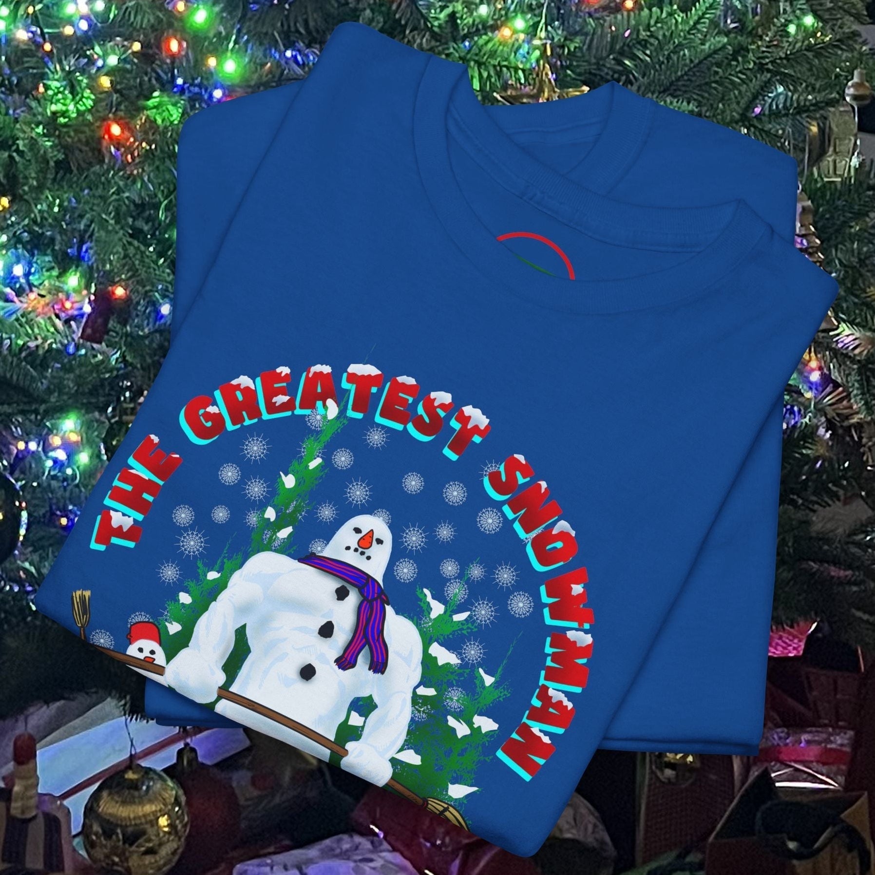 Blue snowman gym t-shirt with funny Christmas workout design folded under decorated Christmas tree lights