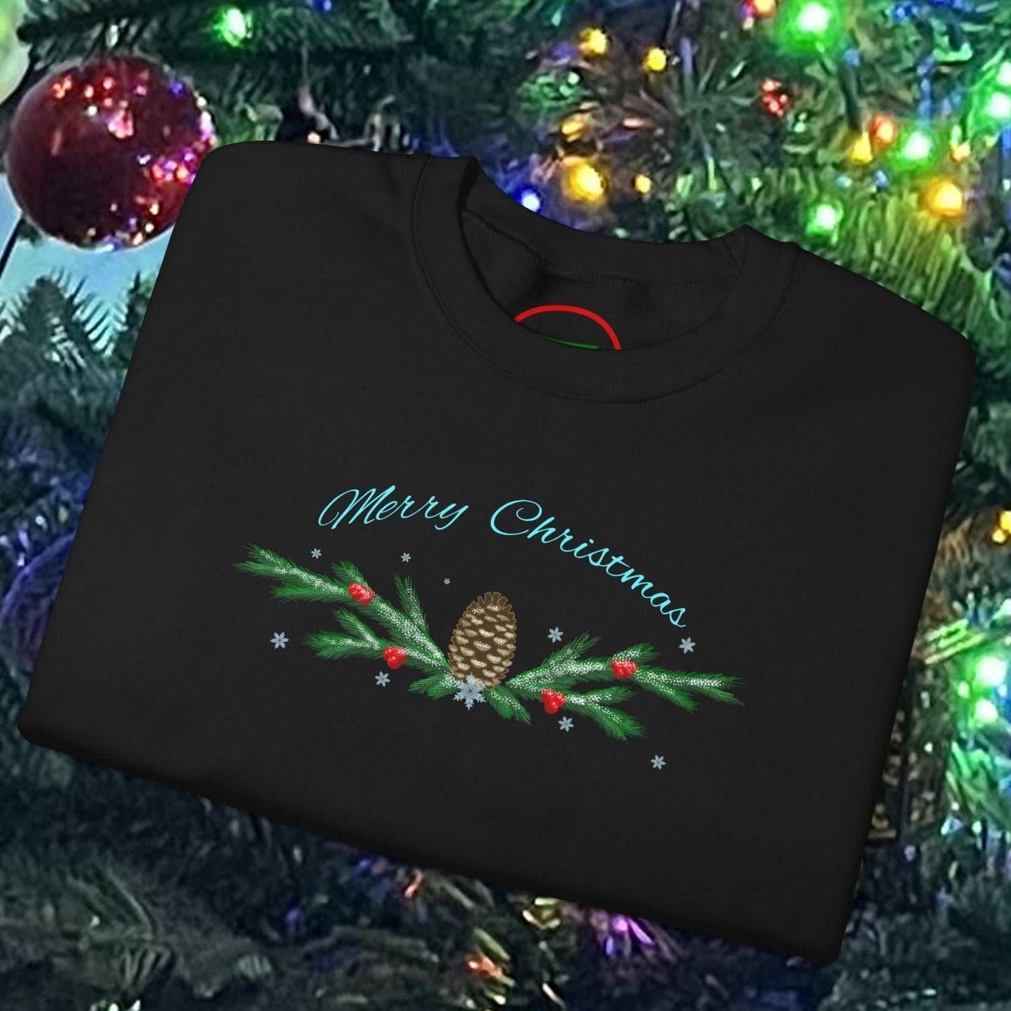 Folded black Pinecone Christmas Sweatshirt with festive pinecone and greenery design on Christmas tree background with colorful lights