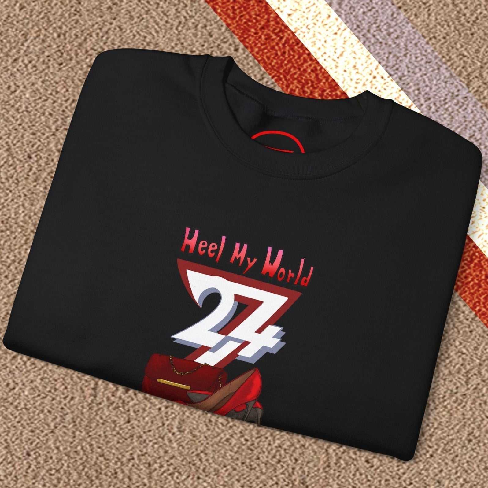 Folded black graphic sweatshirt for women with handbag and high-heel design and "Heel My World" text on carpet background