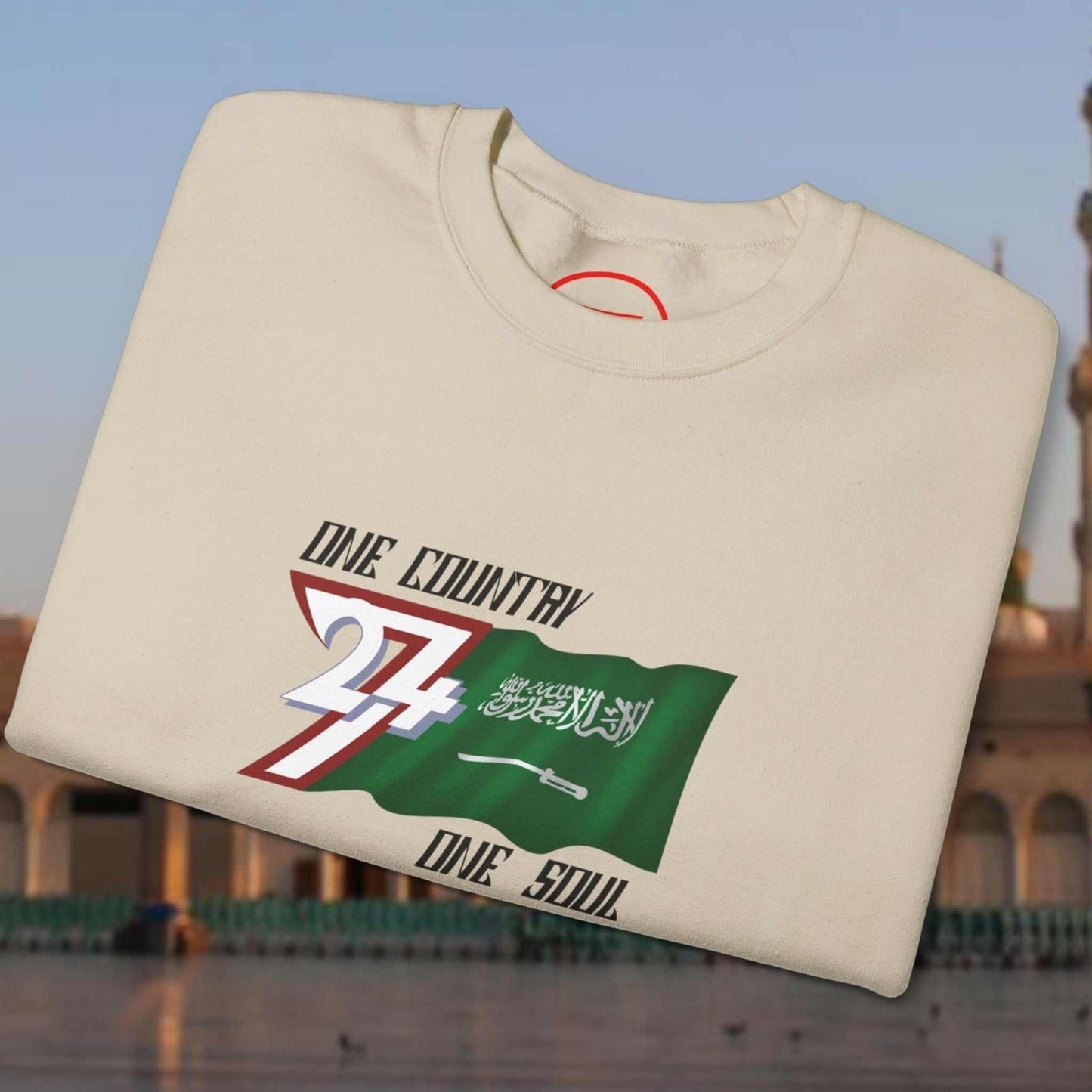 Folded cream crewneck sweatshirt with hand-drawn Saudi Arabia flag and patriotic text design
