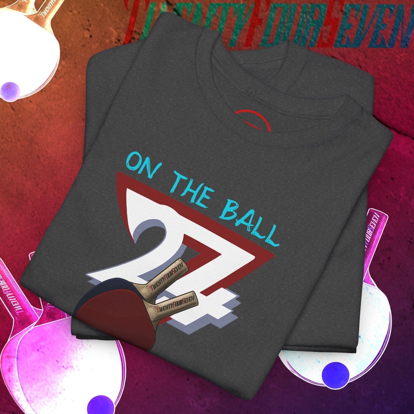 Folded dark gray Table Tennis T-Shirt with hand-drawn 90s style ping pong graphic and "On The Ball" text on front