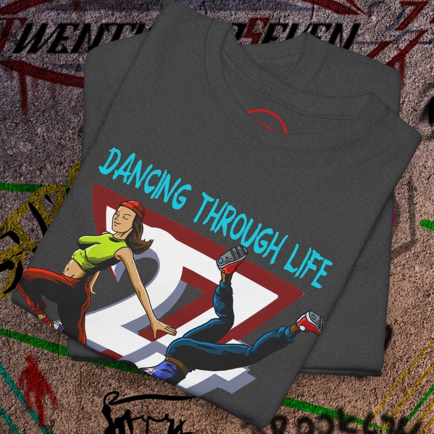 Folded dark gray dance t-shirt with colorful 90s funky comic-style dancers print and "Dancing Through Life" text on urban background
