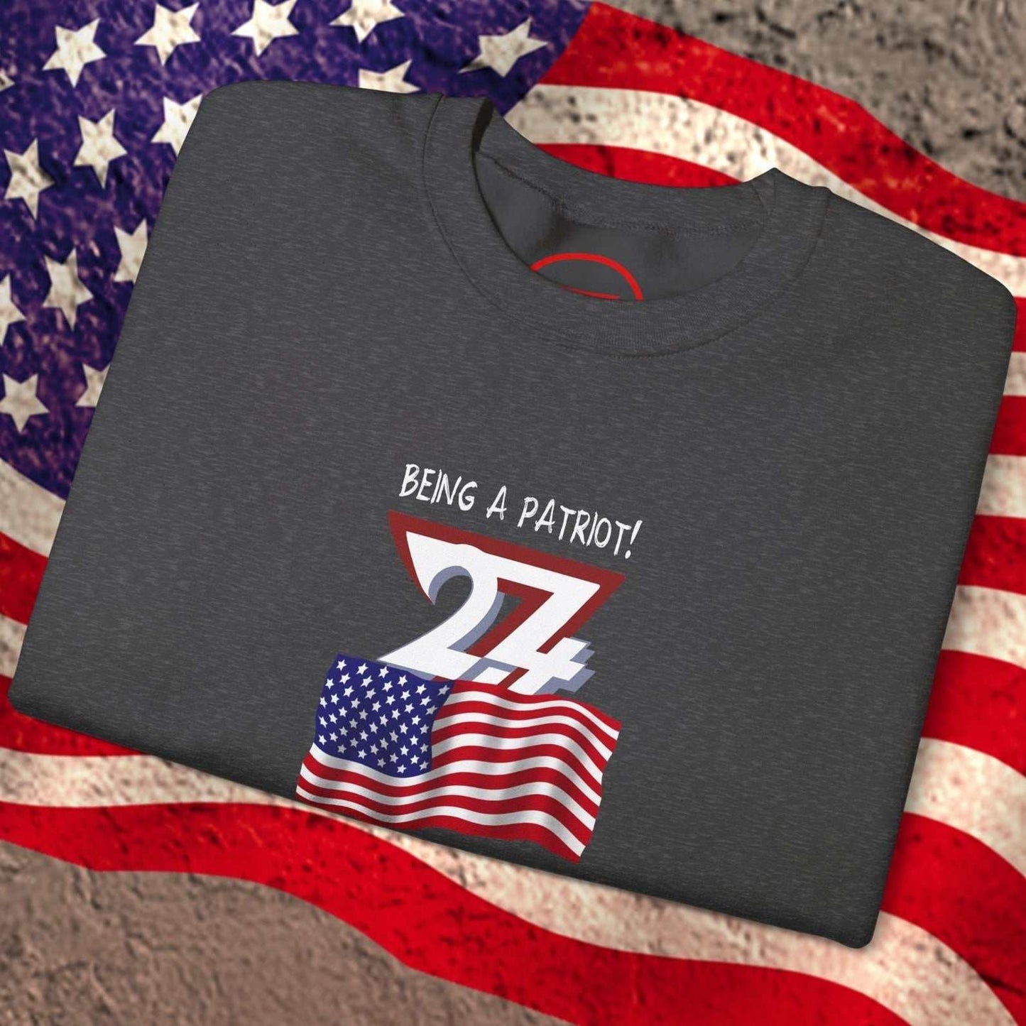 Folded dark gray sweatshirt with hand-drawn American flag and "Being a Patriot!" text on flag background