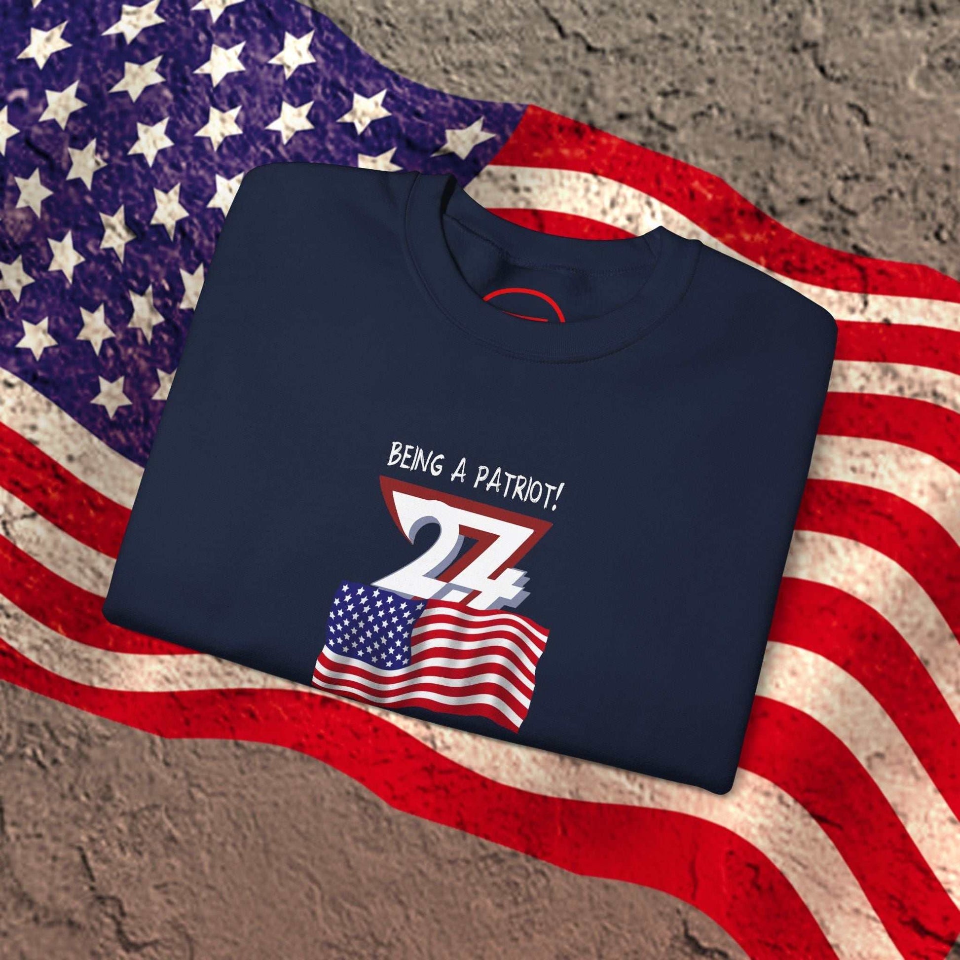 Folded navy blue American Flag Patriot Sweatshirt with hand-drawn flag design on textured surface and American flag background