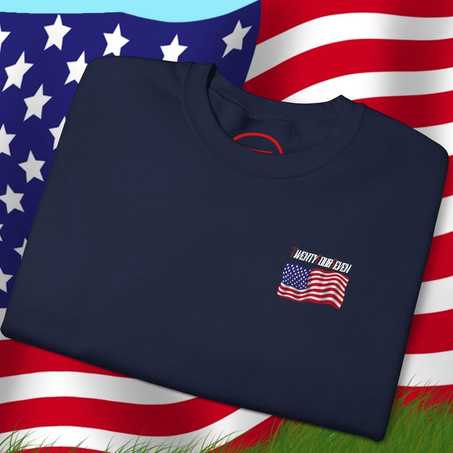 Folded navy blue US flag sweatshirt with hand-drawn American flag design on front, displayed on waving US flag background