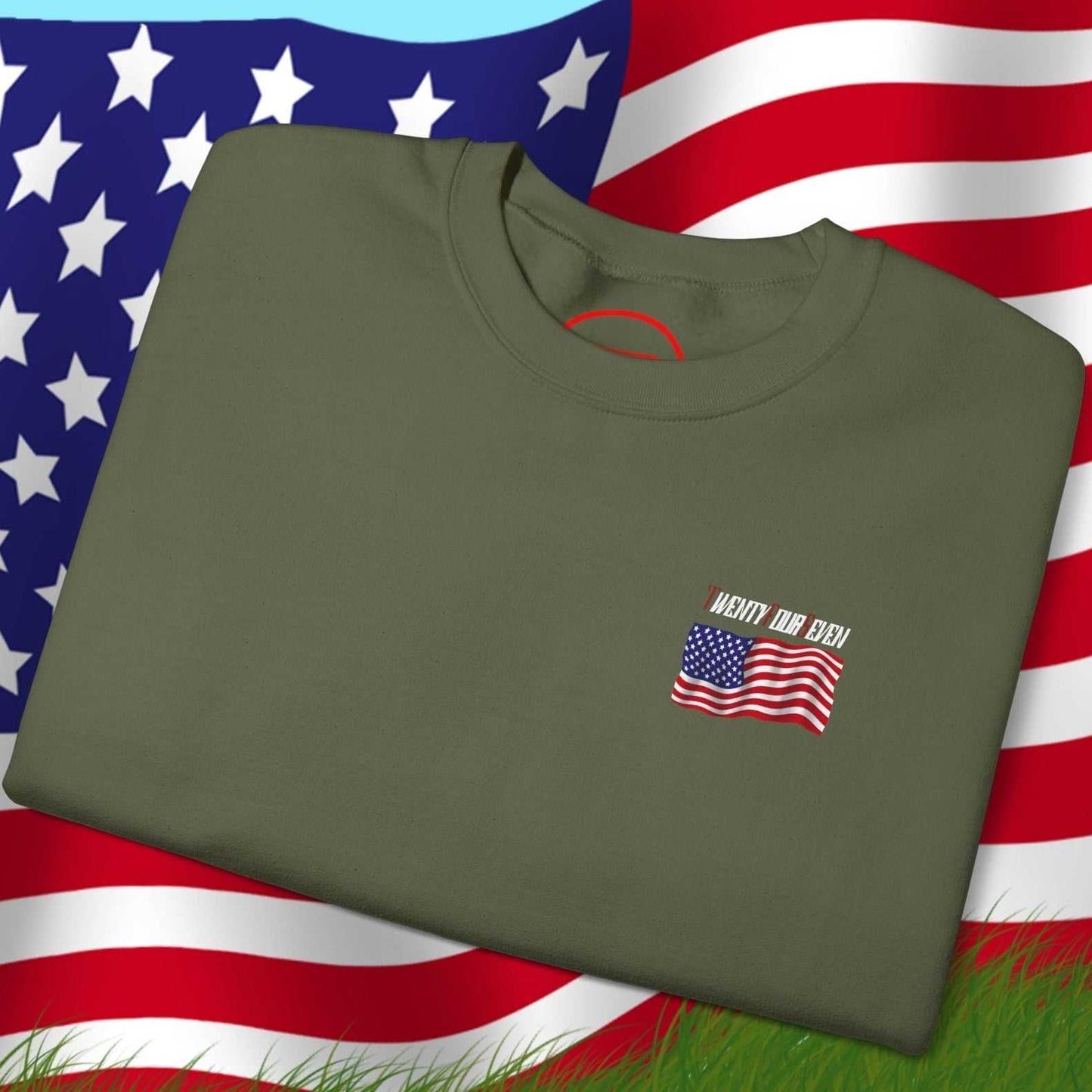 Folded olive green US flag sweatshirt with small patriotic design on front, displayed on American flag background