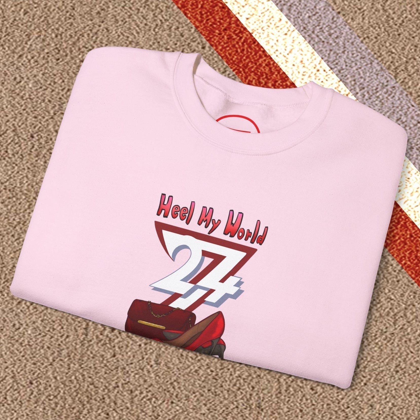 Folded pink graphic sweatshirt for women with handbag and high-heel design on carpet floor