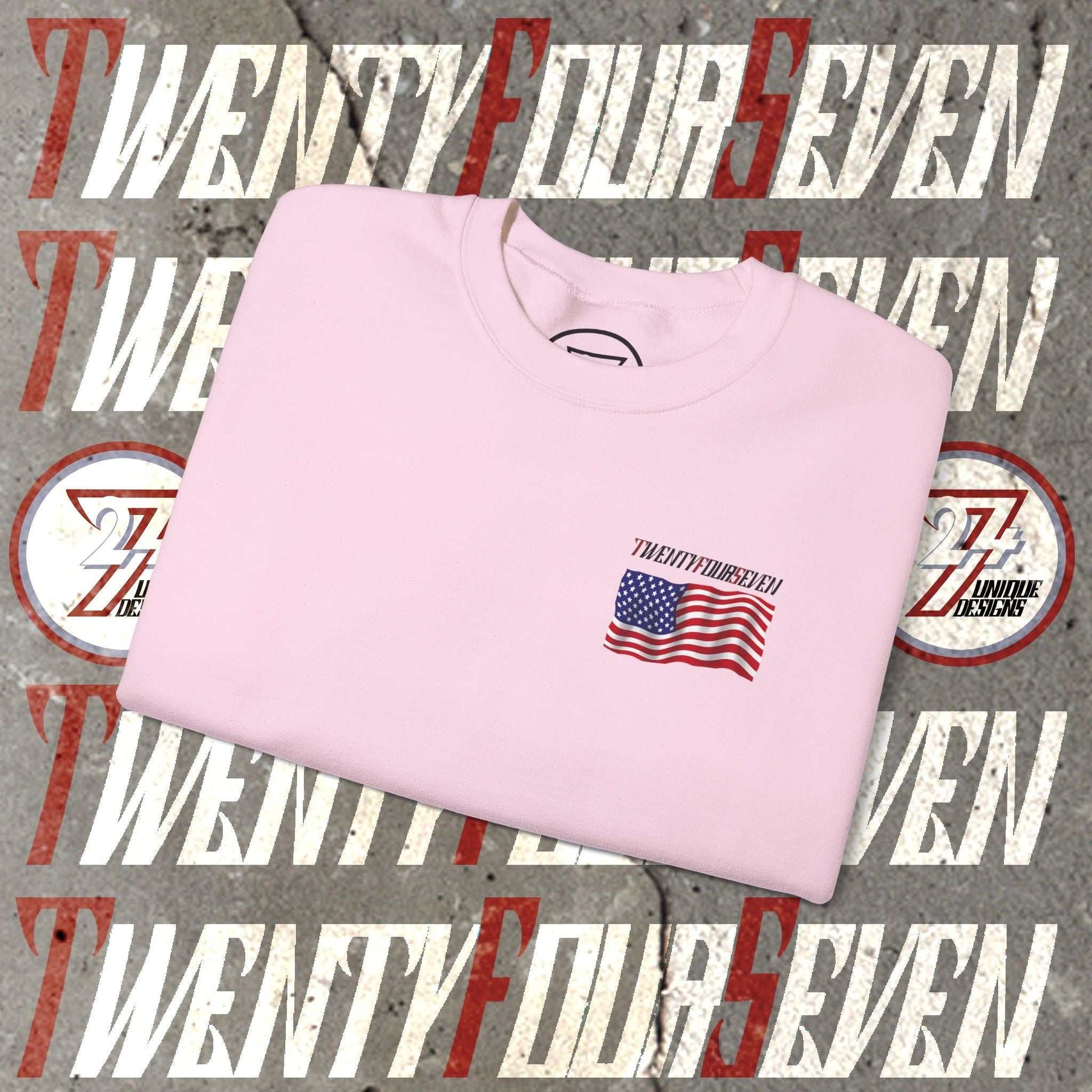 Folded pink sweatshirt with small hand-drawn American flag and "Twenty Four Seven" text design on front against a graphic background