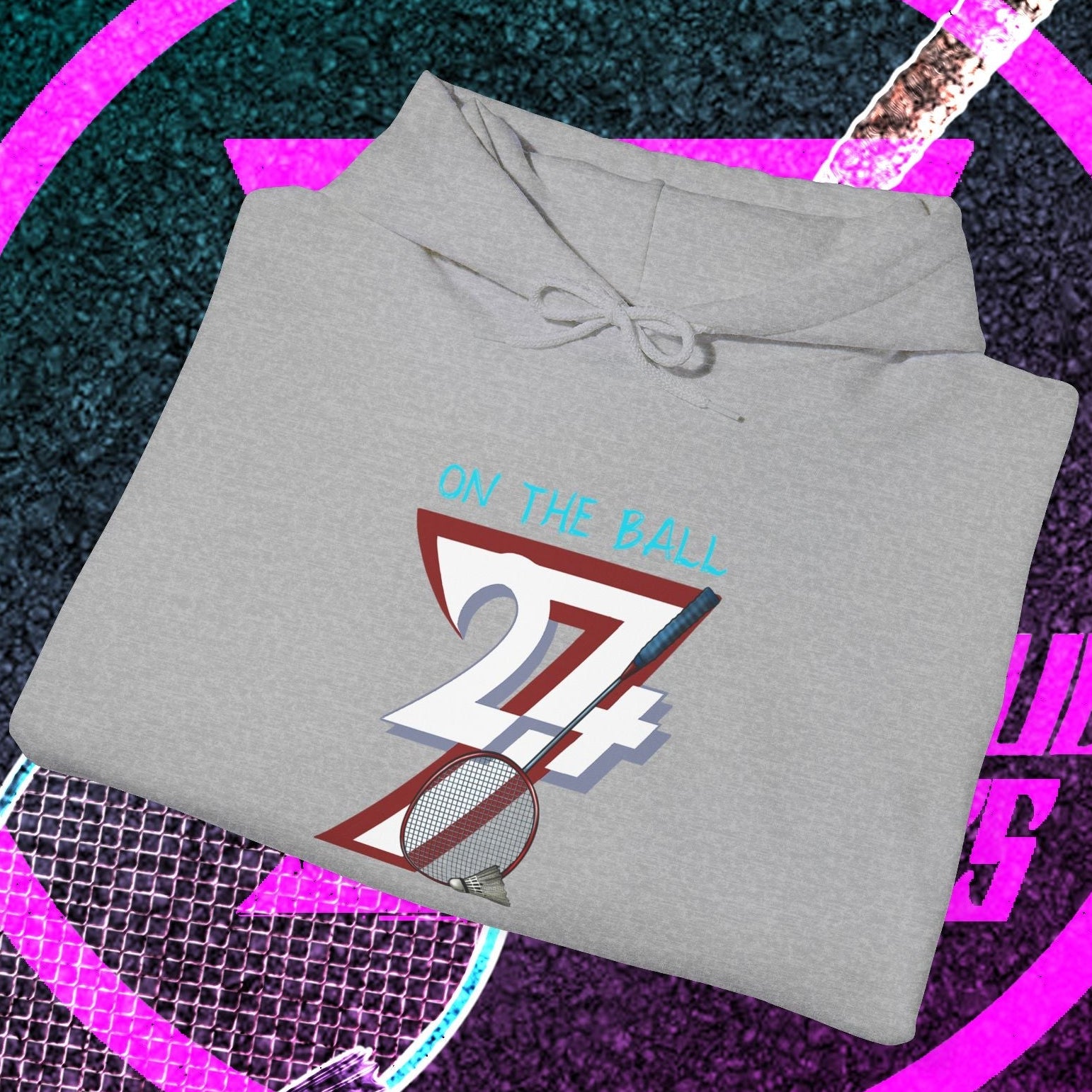Gray badminton hoodie with "On The Ball" graphic and number 24/7 folded on tennis racquet background
