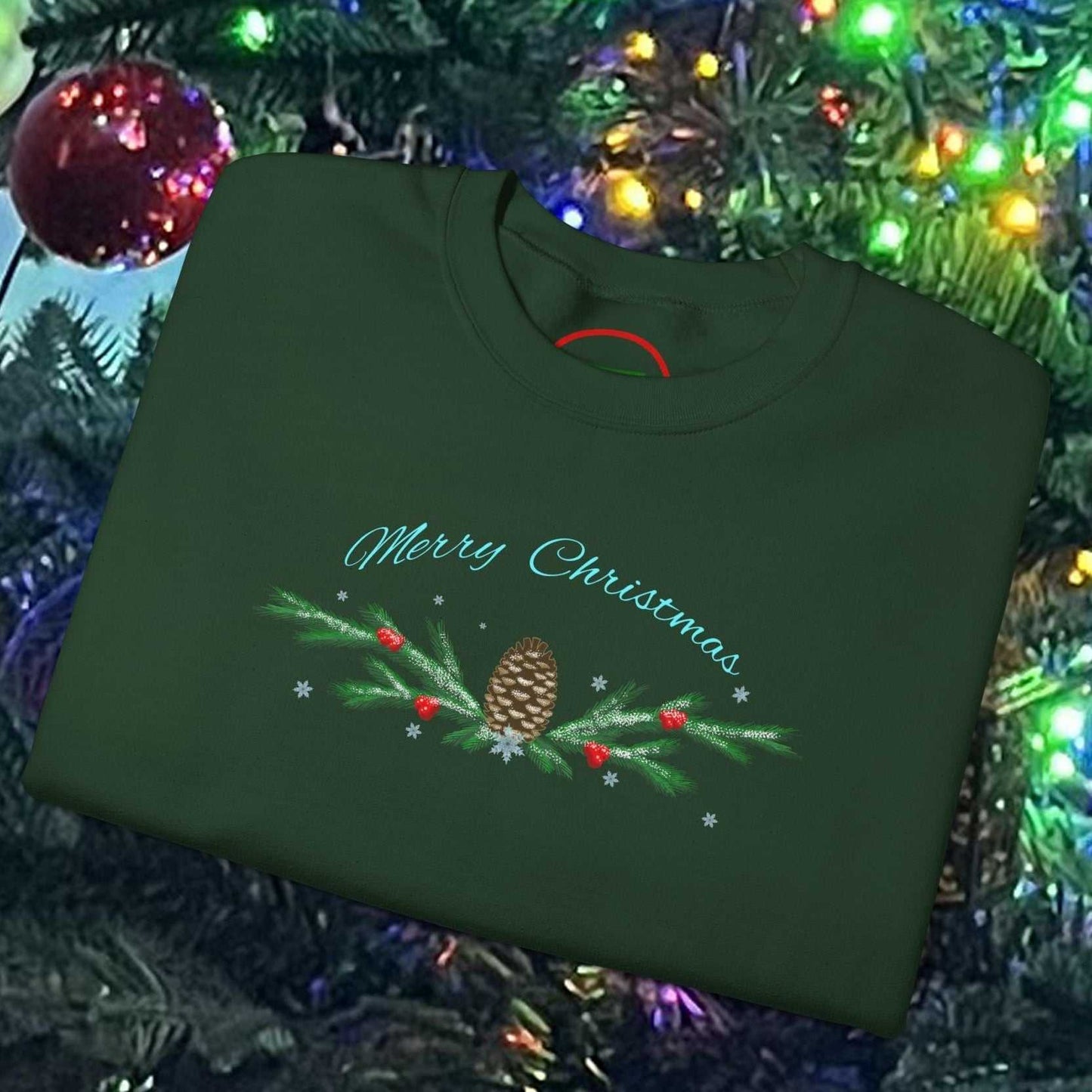 Green Pinecone Christmas Sweatshirt with festive holiday design folded on decorated Christmas tree background