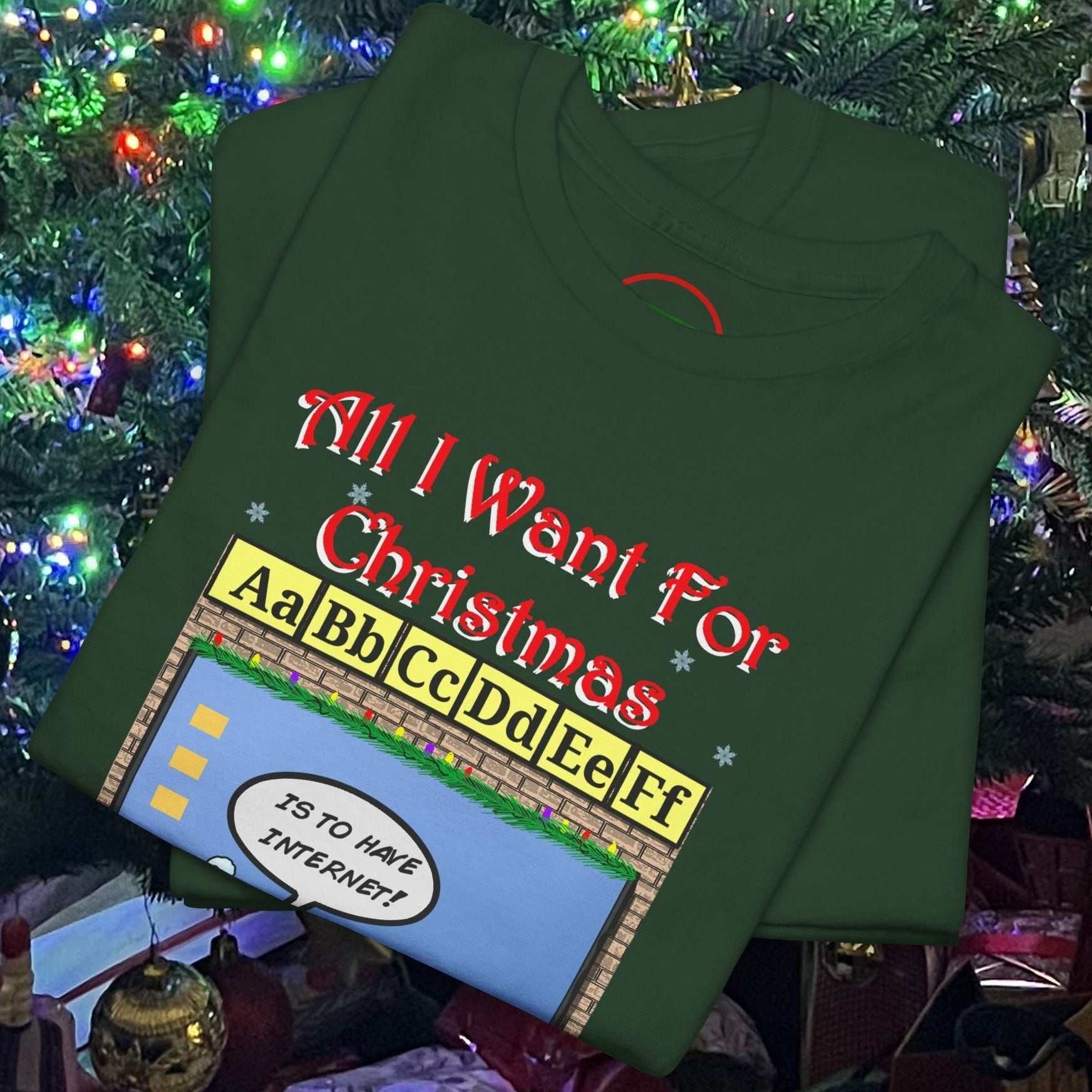Green Teacher Elf T-Shirt with funny Christmas text and colorful alphabet design folded on holiday-decorated background
