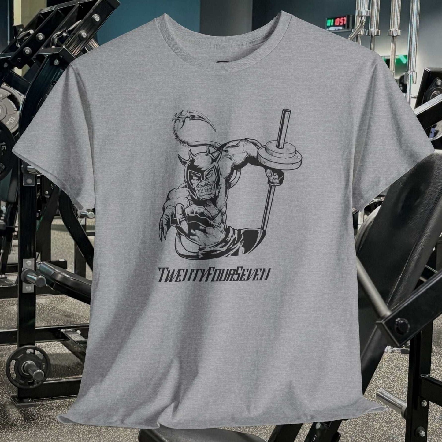 Grey gym tee with hand-drawn comic-style weightlifter illustration and "TwentyFourSeven" text, displayed in gym setting