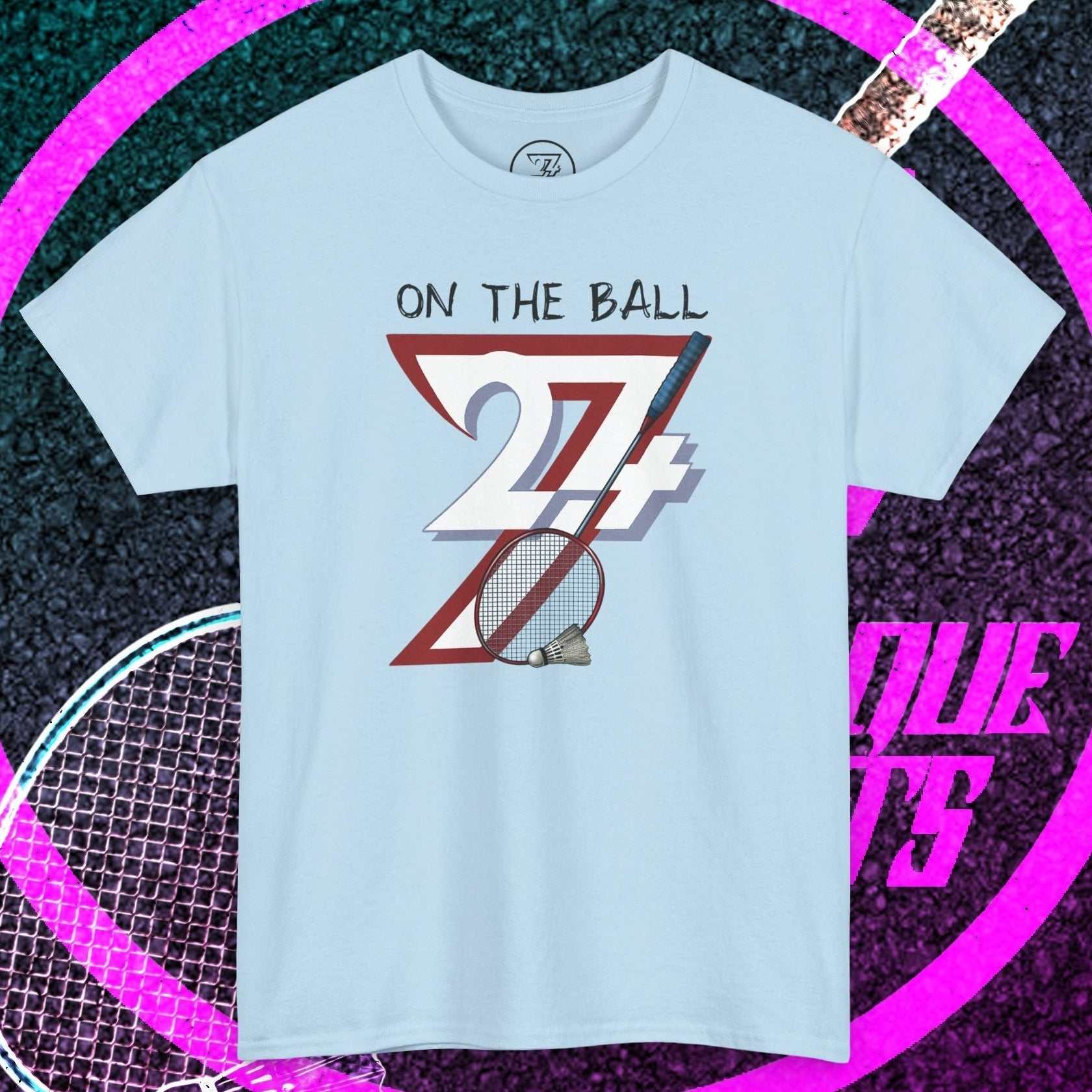 Light blue badminton tee with hand-drawn "On the Ball 24/7" graphic and racket illustration, breathable cotton, classic fit