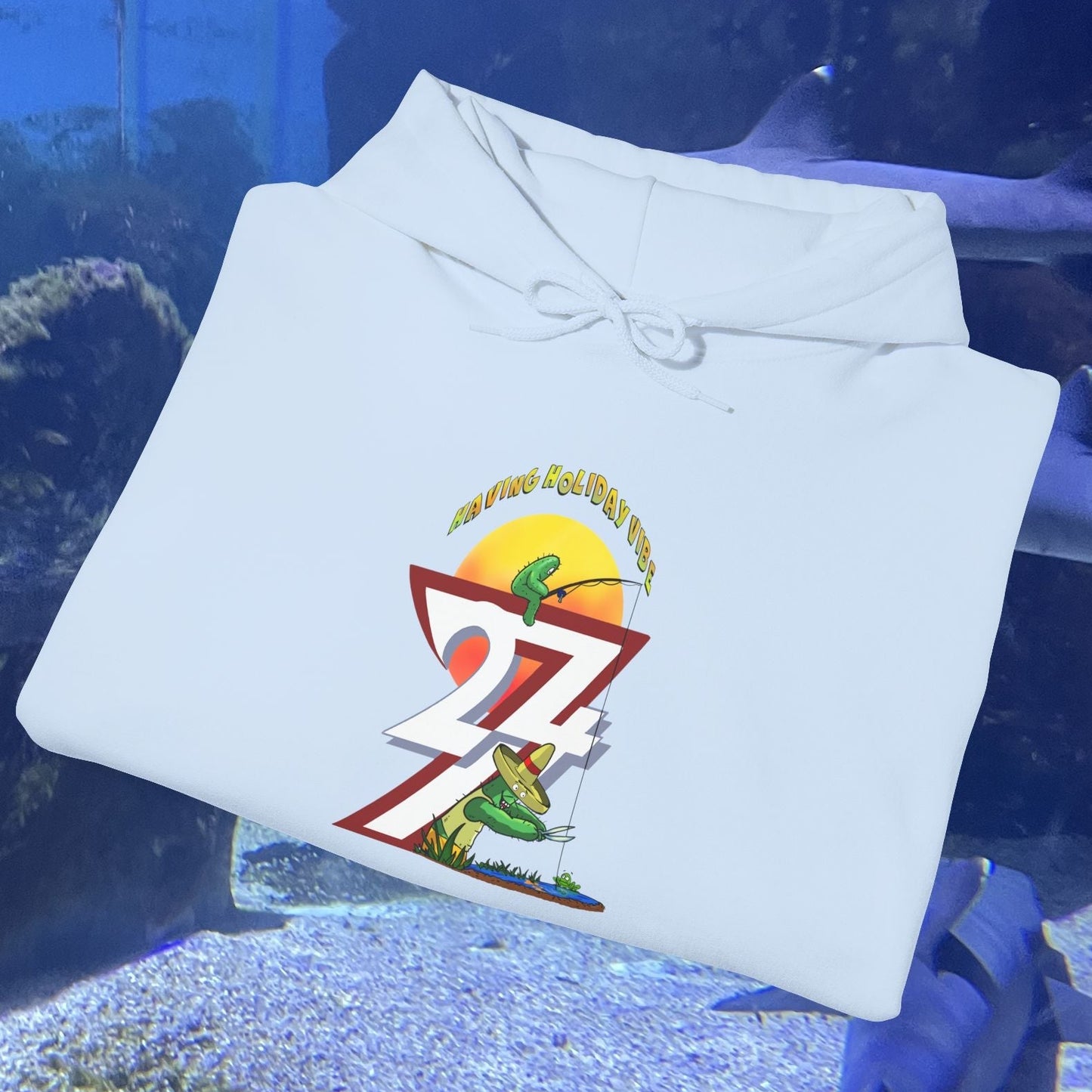 Light blue funny fishing hoodie with cactus and sunset graphic folded on a blue underwater background