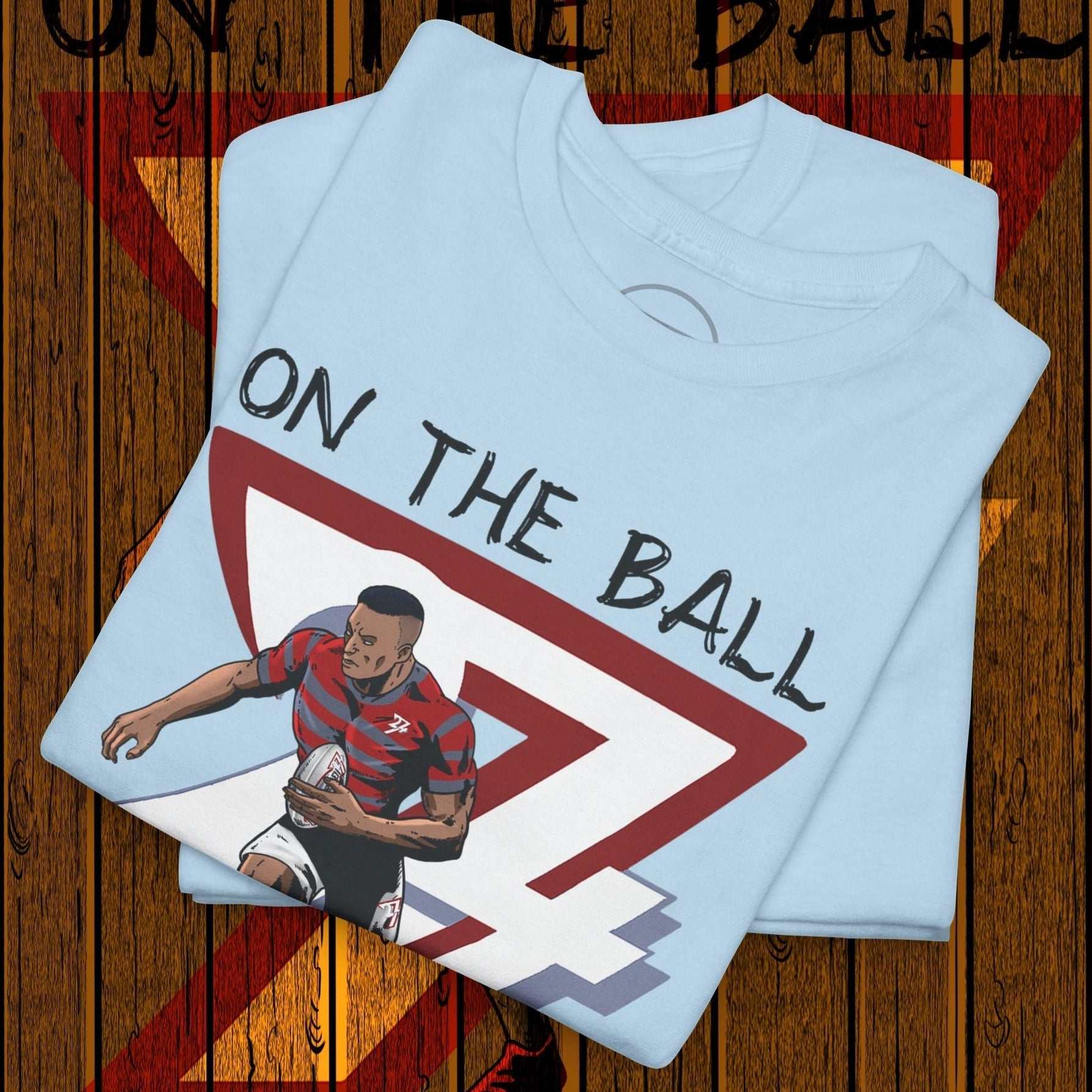 Light blue rugby sports tee with hand-drawn rugby player illustration and "On the Ball" text design