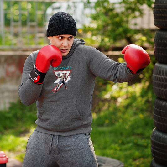Man wearing grey boxing hoodie with hand-drawn boxer design and red gloves training outdoors