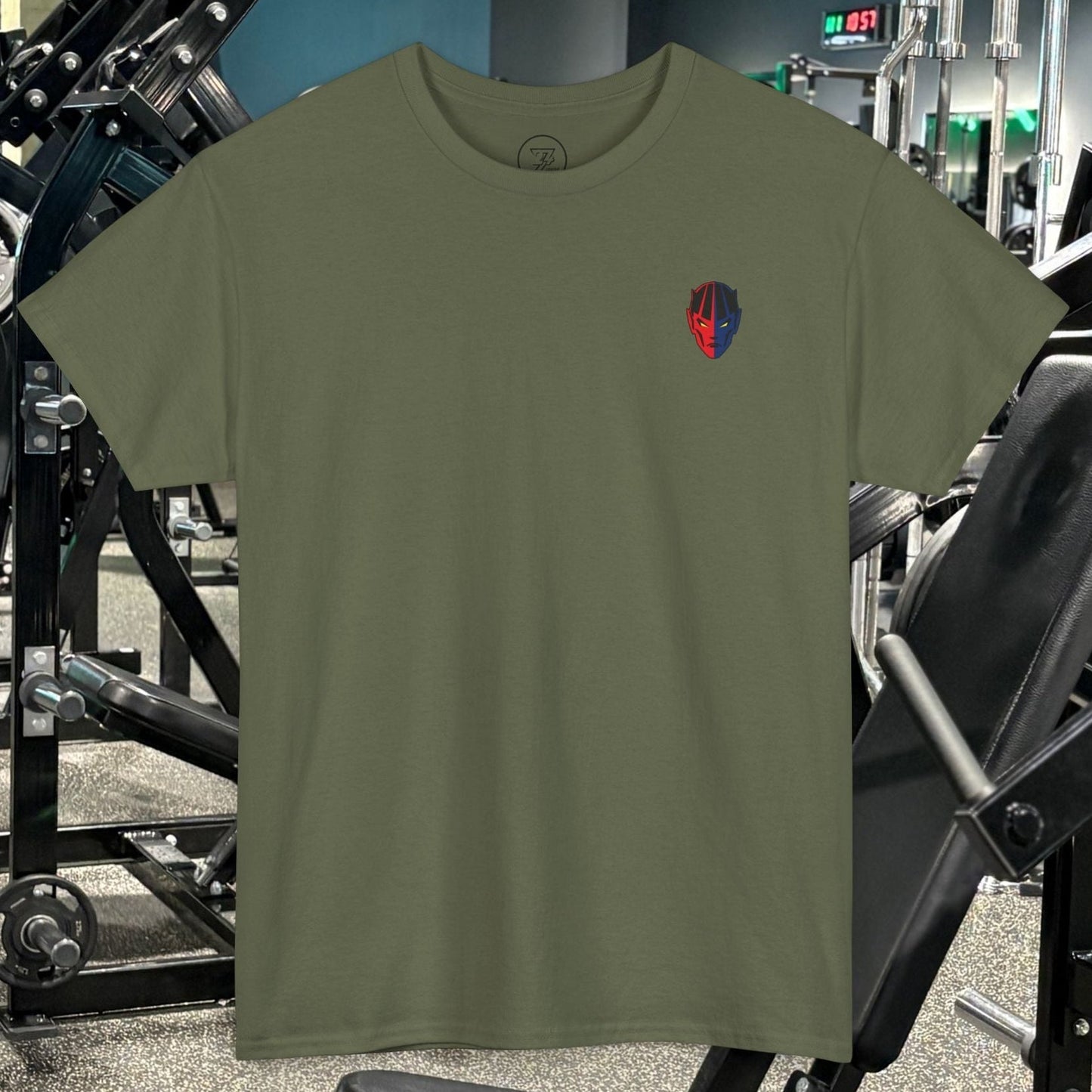 Olive green bodybuilding tee with small red and blue comic-style graphic on chest, displayed in gym setting