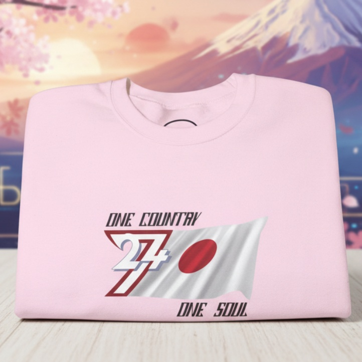 Pink Japan Flag Crewneck Sweatshirt with hand-drawn sun-disk design and "One Country One Soul" text, displayed with Mount Fuji and cherry blossoms background