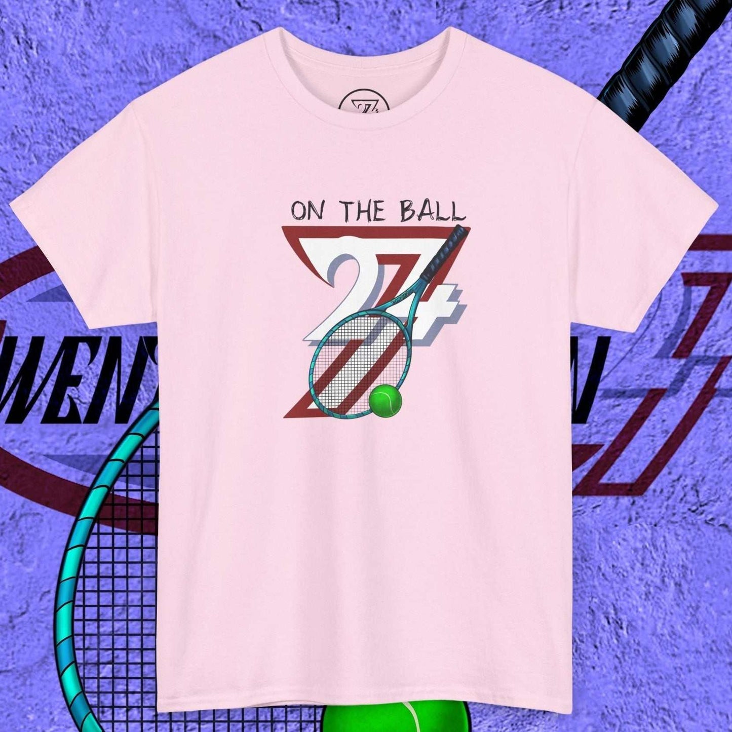 Pink tennis tee with hand-drawn "On the Ball 24/7" graphic featuring a racket and tennis ball
