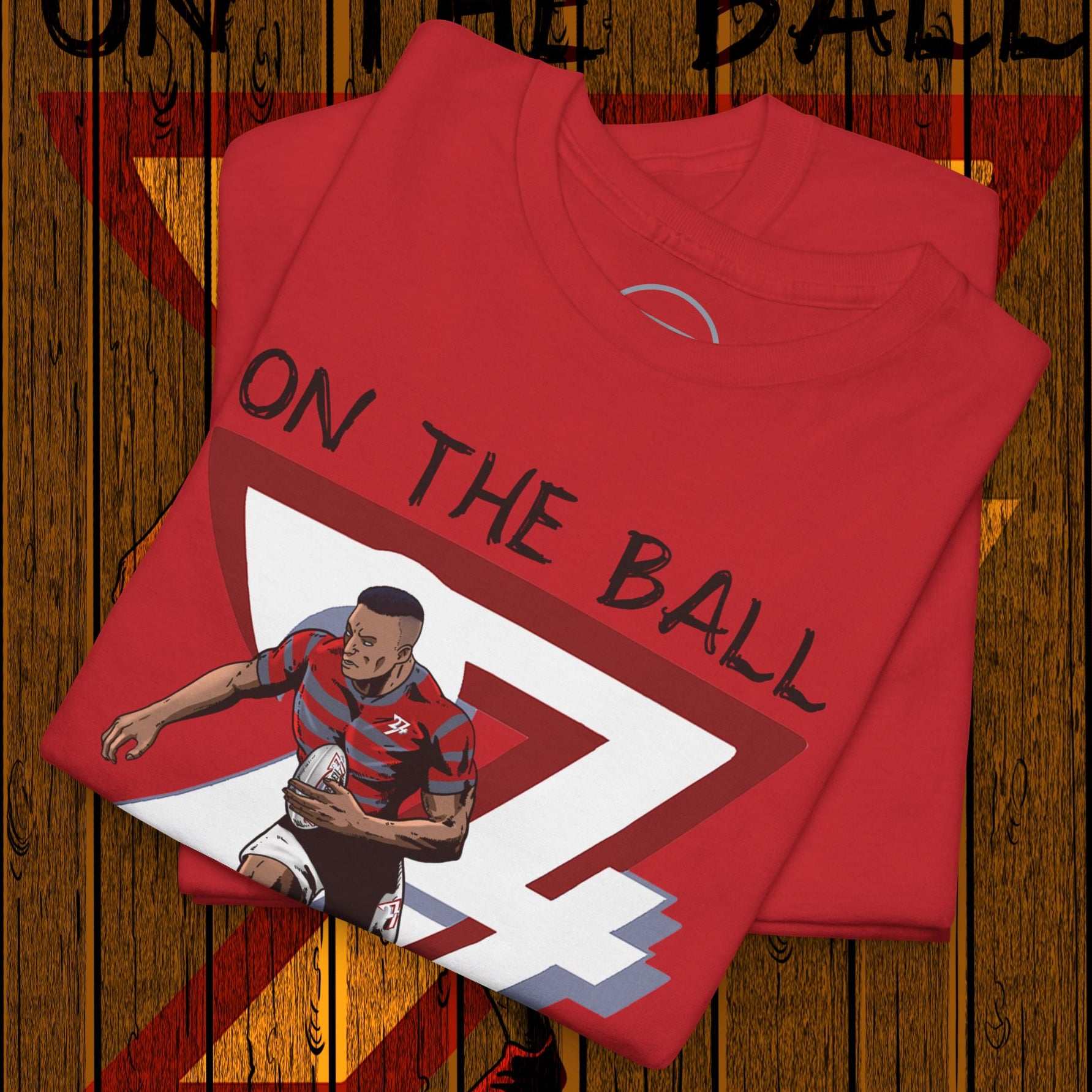 Red rugby sports tee with hand-drawn player illustration and "On The Ball" text on wooden background