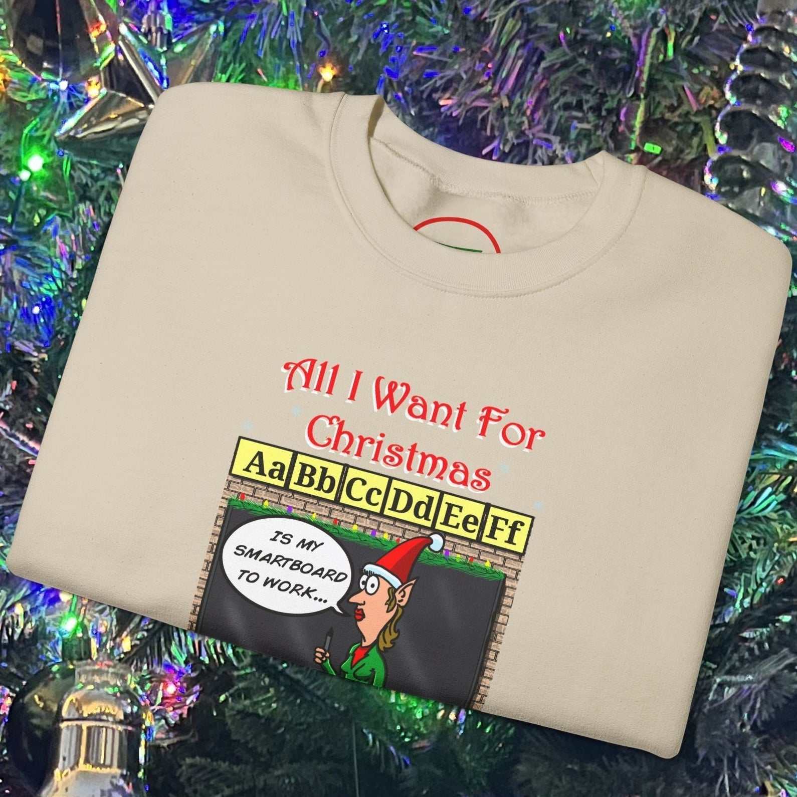 Teacher Christmas sweatshirt with funny cartoon classroom design folded on decorated Christmas tree background