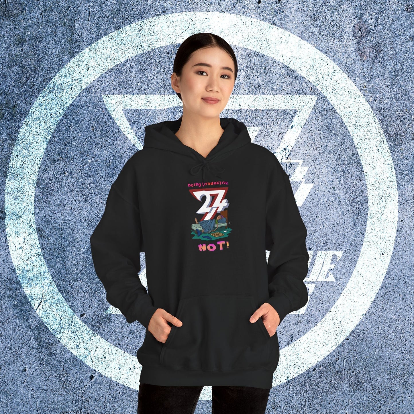 Teen wearing black funny custom hoodie with colorful lazy cartoon design and kangaroo pocket standing against textured blue background