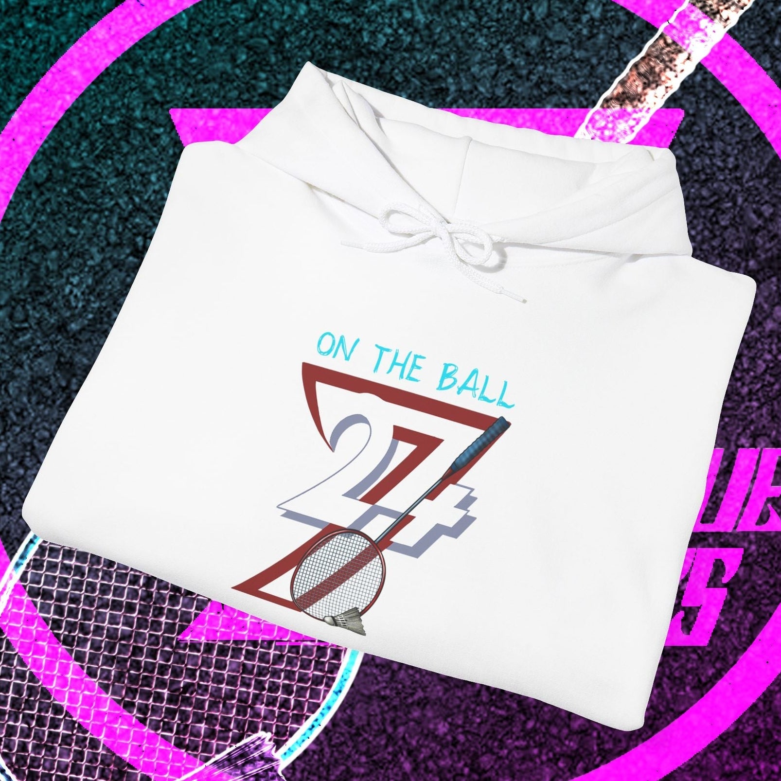 White badminton hoodie with "On The Ball" graphic and drawstring hood, folded on a vibrant badminton-themed background